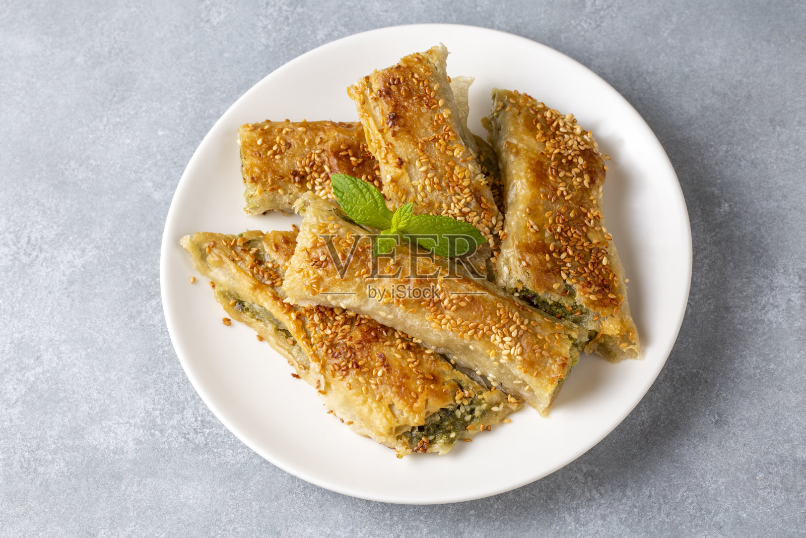 希腊菜;烤箱里手工制作的菠菜羊乳酪派上芝麻。土耳其的名字;ispanakli borek照片摄影图片