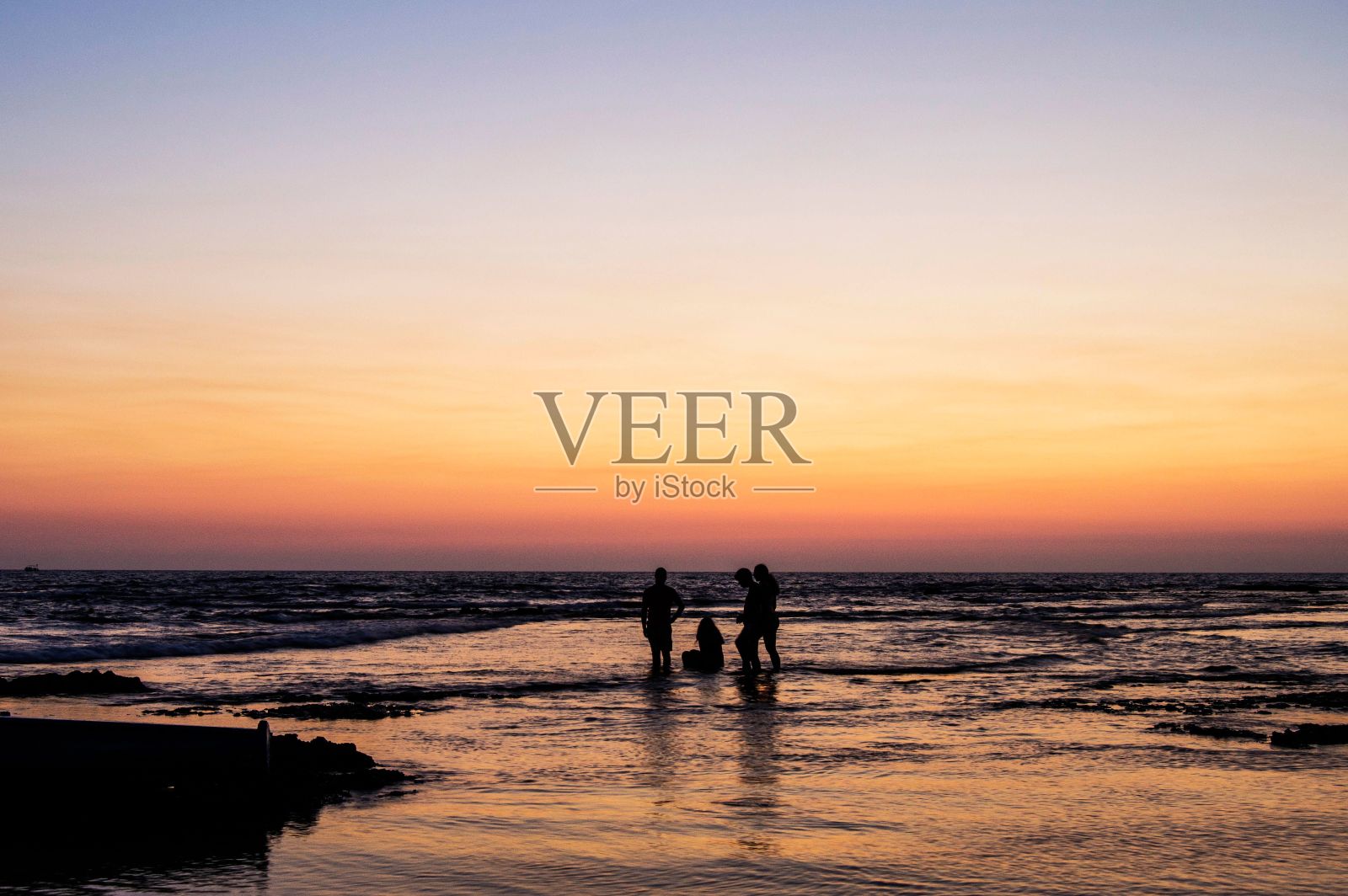 日落时分人们站在海滩上的剪影照片摄影图片