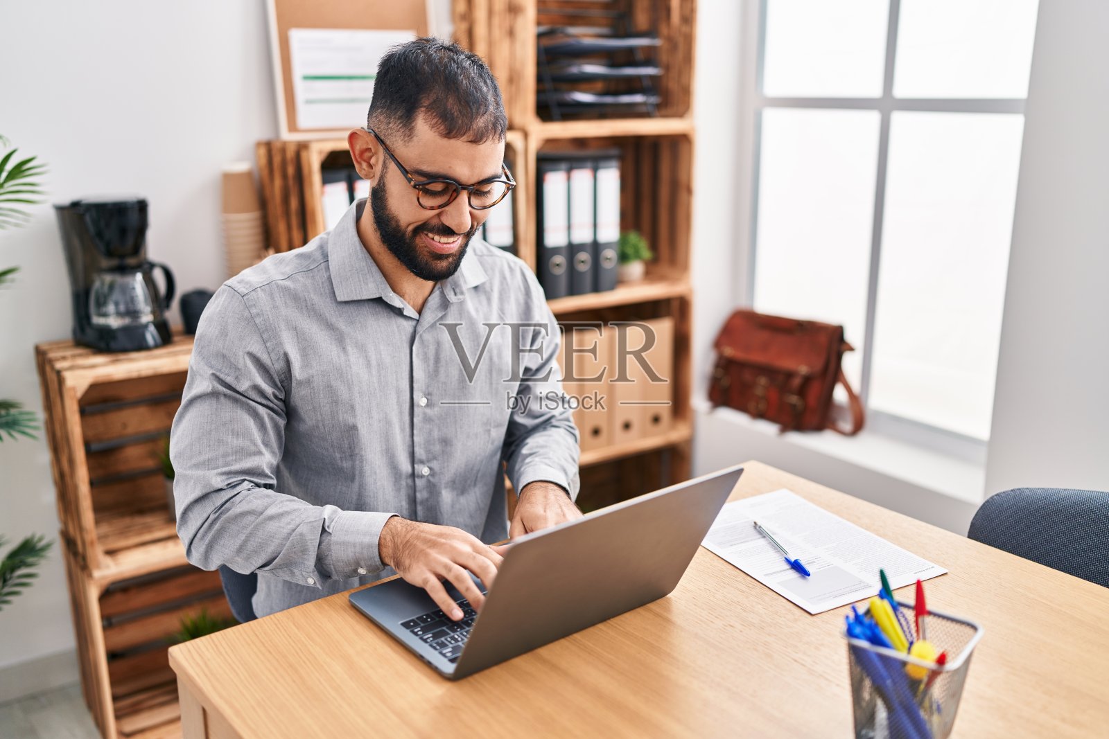 年轻的西班牙人工作人员使用笔记本电脑在办公室工作照片摄影图片