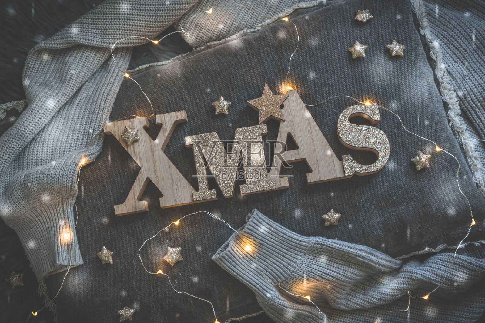 用大写大写的木制大写字母写着“圣诞”，放在一个灰色的枕头上，上面有仙女灯照片摄影图片