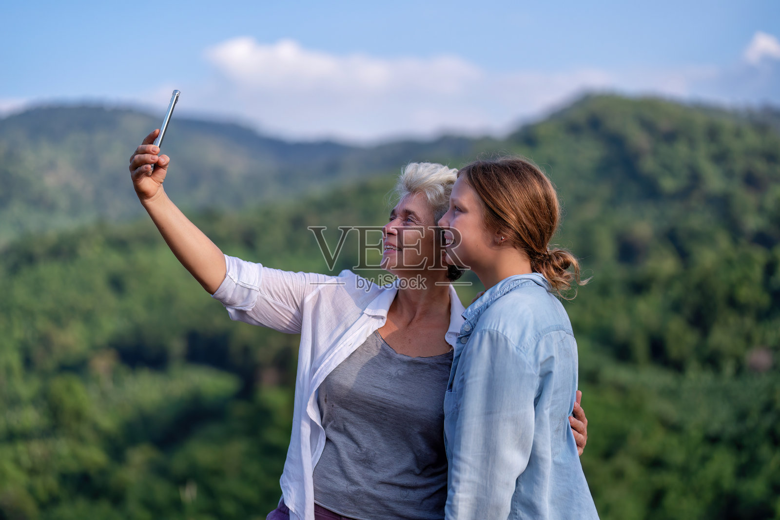 背包冒险徒步旅行者母女在山上用智能手机拍照照片摄影图片