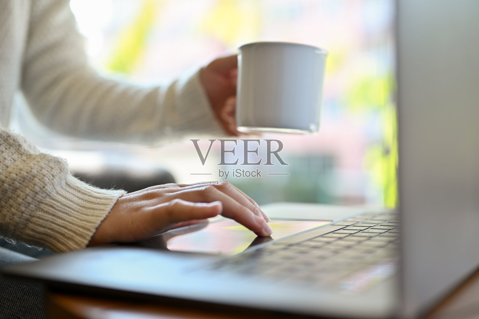 一位女性自由职业者在咖啡店远程工作，一边喝咖啡一边用笔记本电脑。照片摄影图片