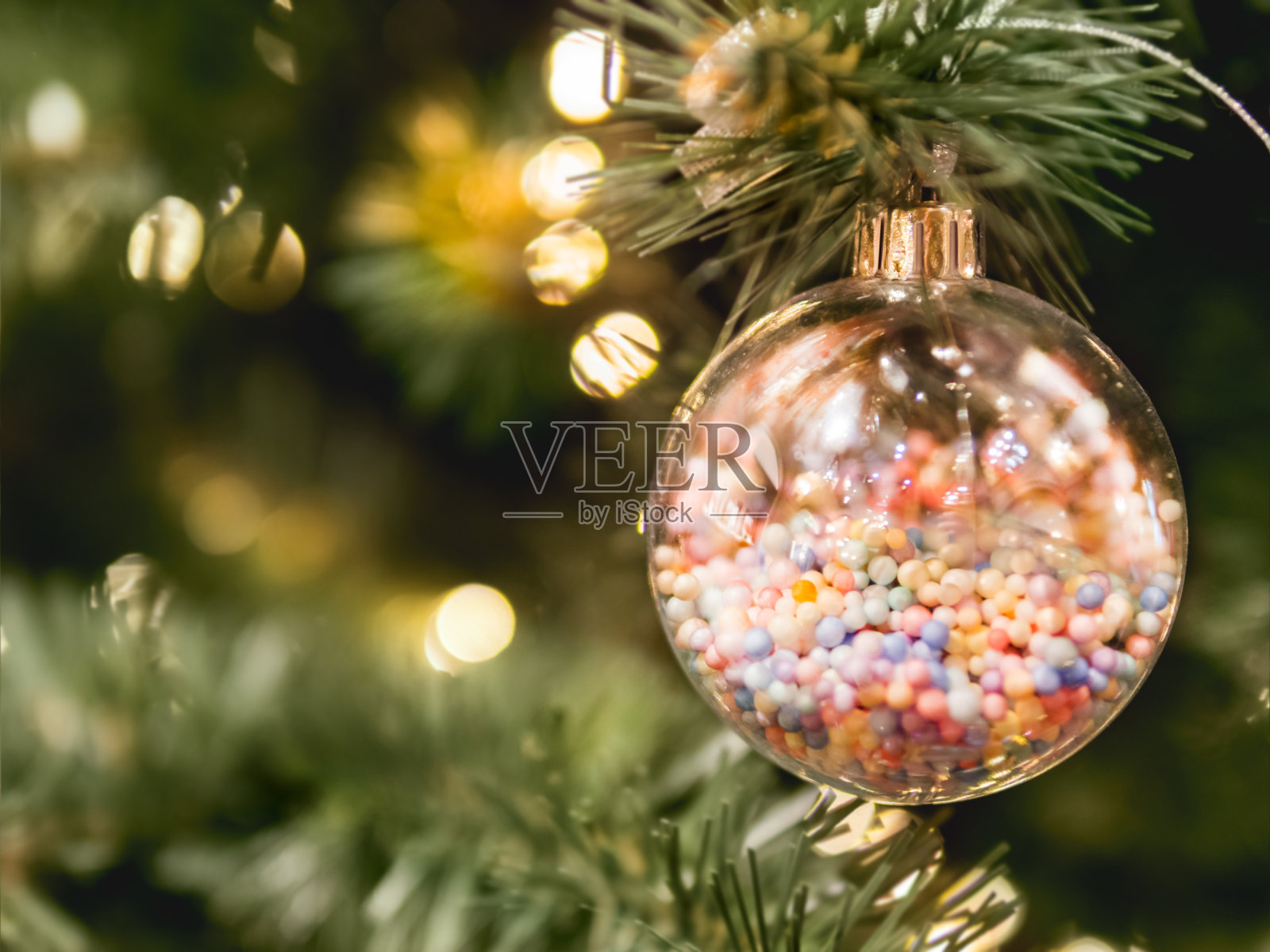 用透明的玻璃球和里面的小糖果装饰的圣诞树。新年庆祝的甜蜜装饰。照片摄影图片