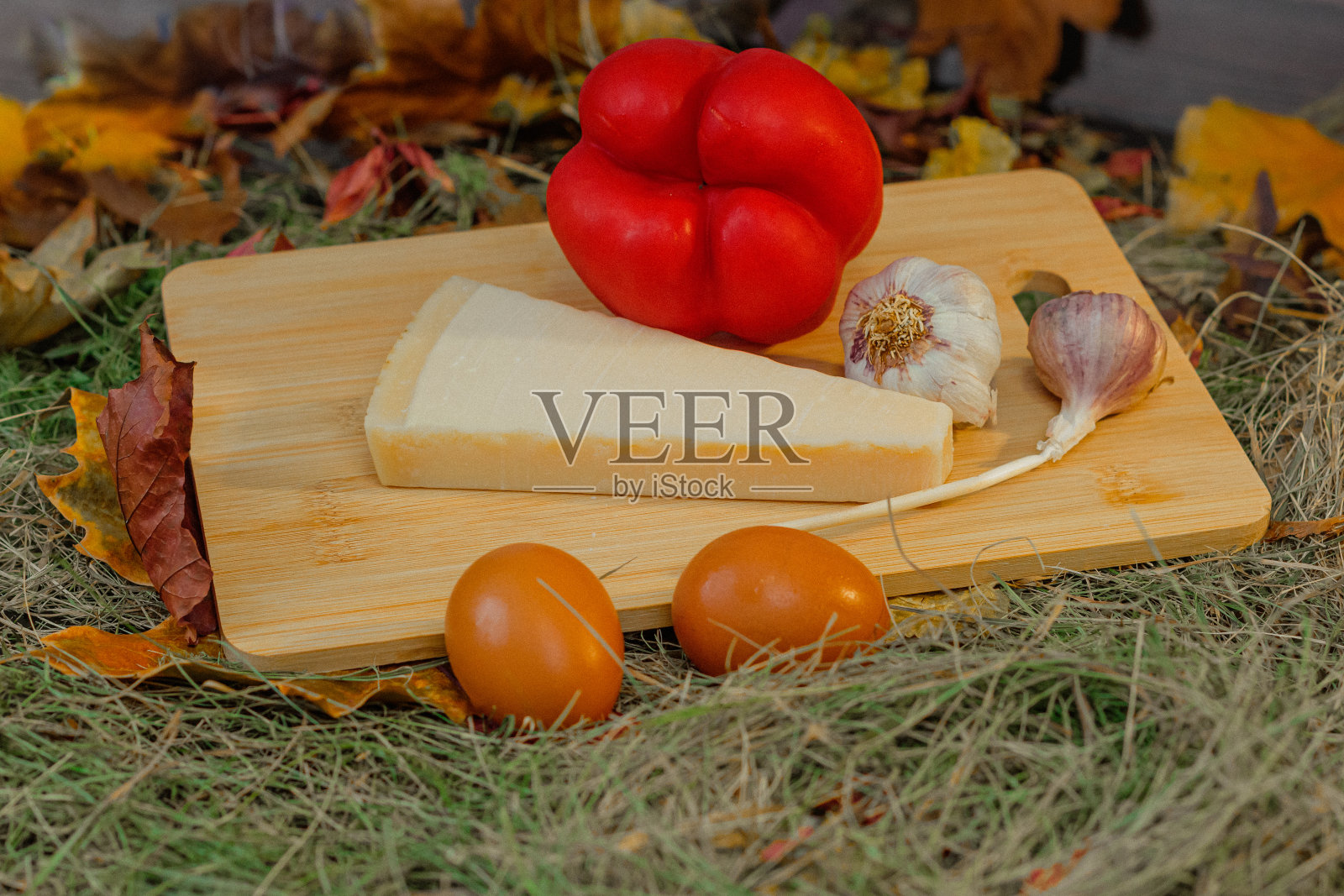 静物，蔬菜和奶酪放在干草上的砧板上照片摄影图片