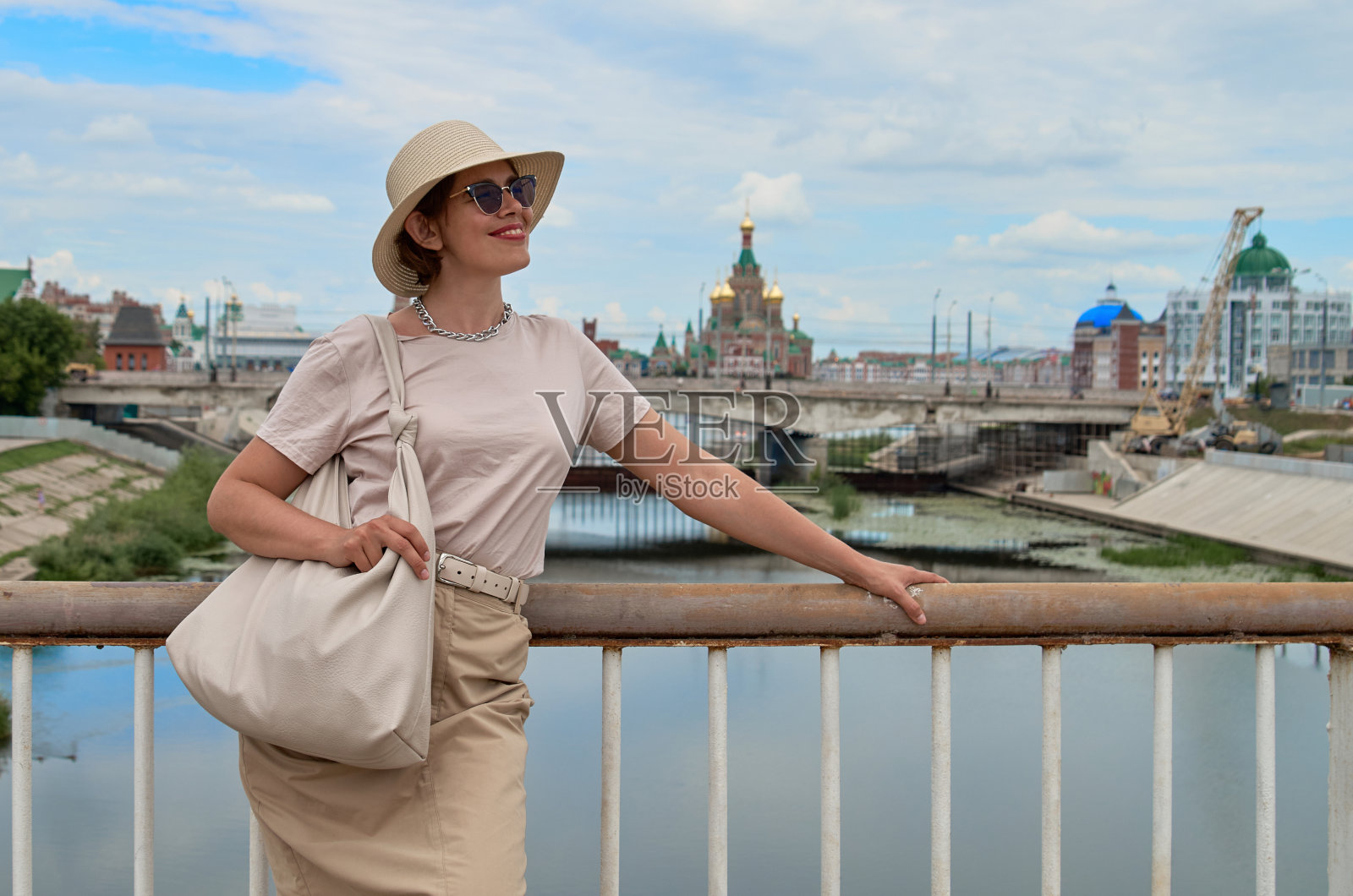 以河流和城市为背景的戴着帽子的旅行妇女的肖像照片摄影图片