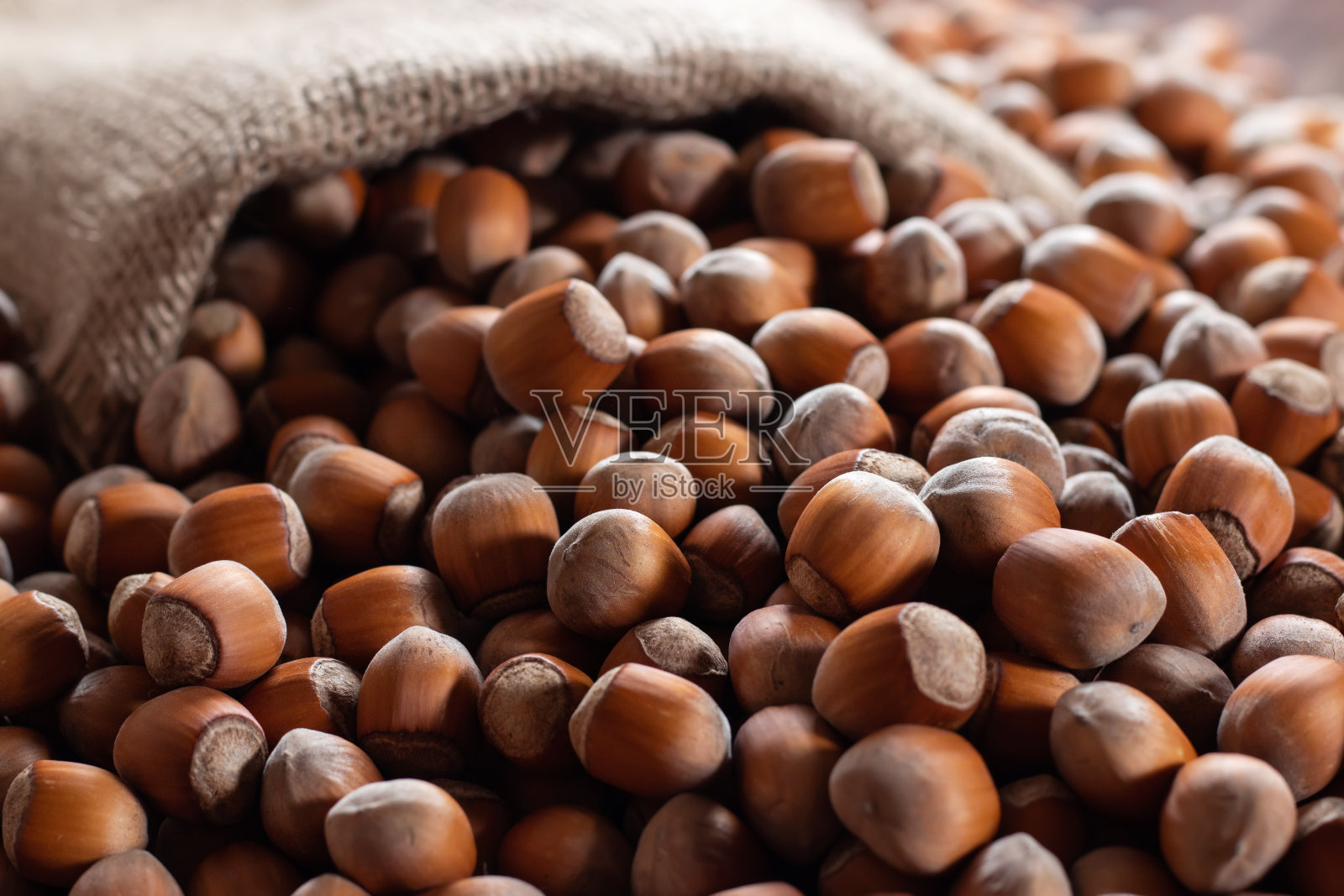 榛子，粗麻袋里的榛子，木制背景。一堆或一堆榛子。榛果背景，健康食品照片摄影图片