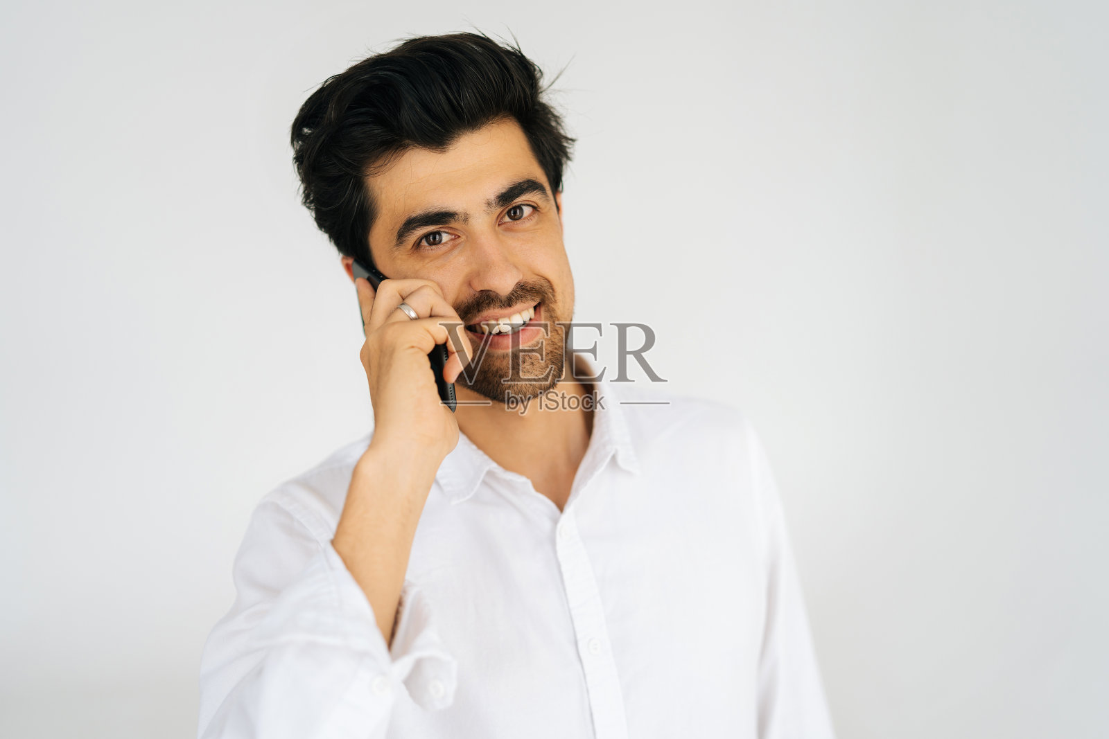 特写肖像友好的年轻人在衬衫说话的智能手机，通话的移动电话，持有和使用手机照片摄影图片