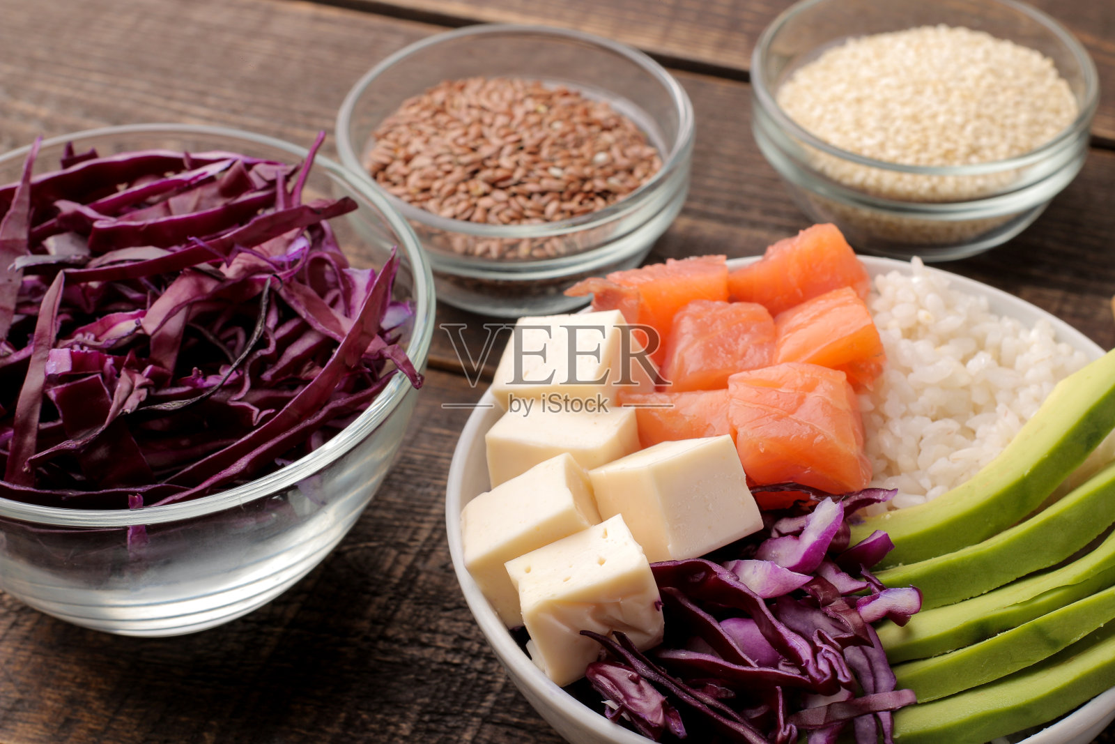 夏威夷菜。一盘米饭，三文鱼，牛油果，卷心菜和奶酪，接近芝麻。在一张棕色的木桌上。照片摄影图片