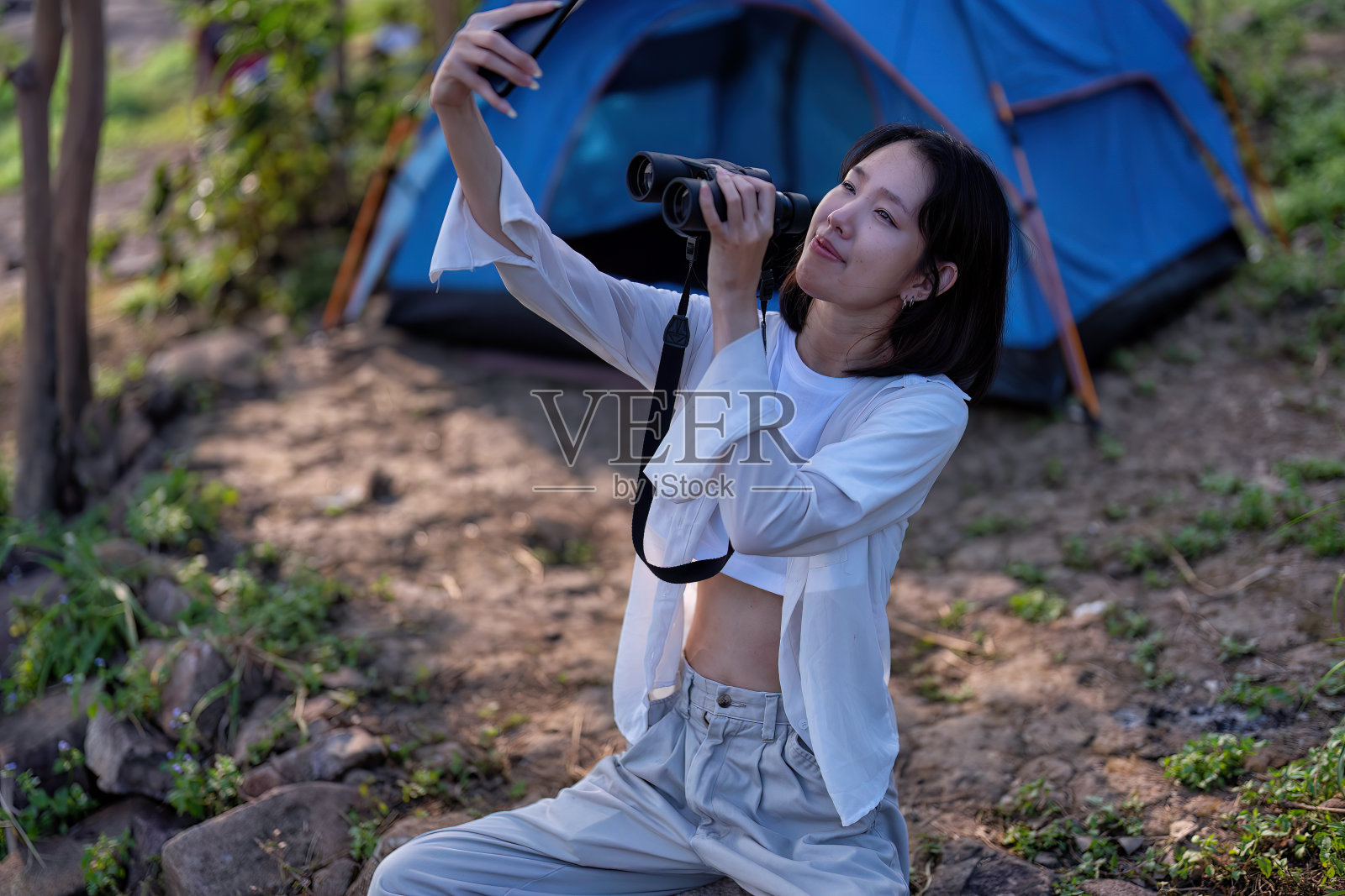 背包冒险远足女孩露营坐在帐篷附近用手机自拍用望远镜看风景照片摄影图片