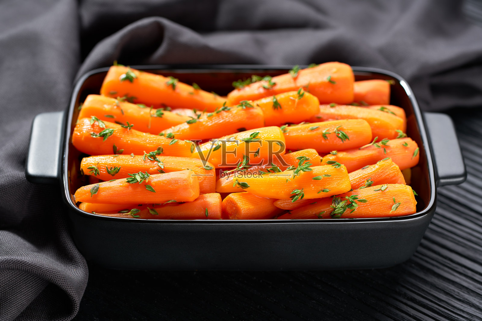 烤成陶瓷形状的小胡萝卜放在深色的木桌上。健康根类蔬菜的概念。照片摄影图片