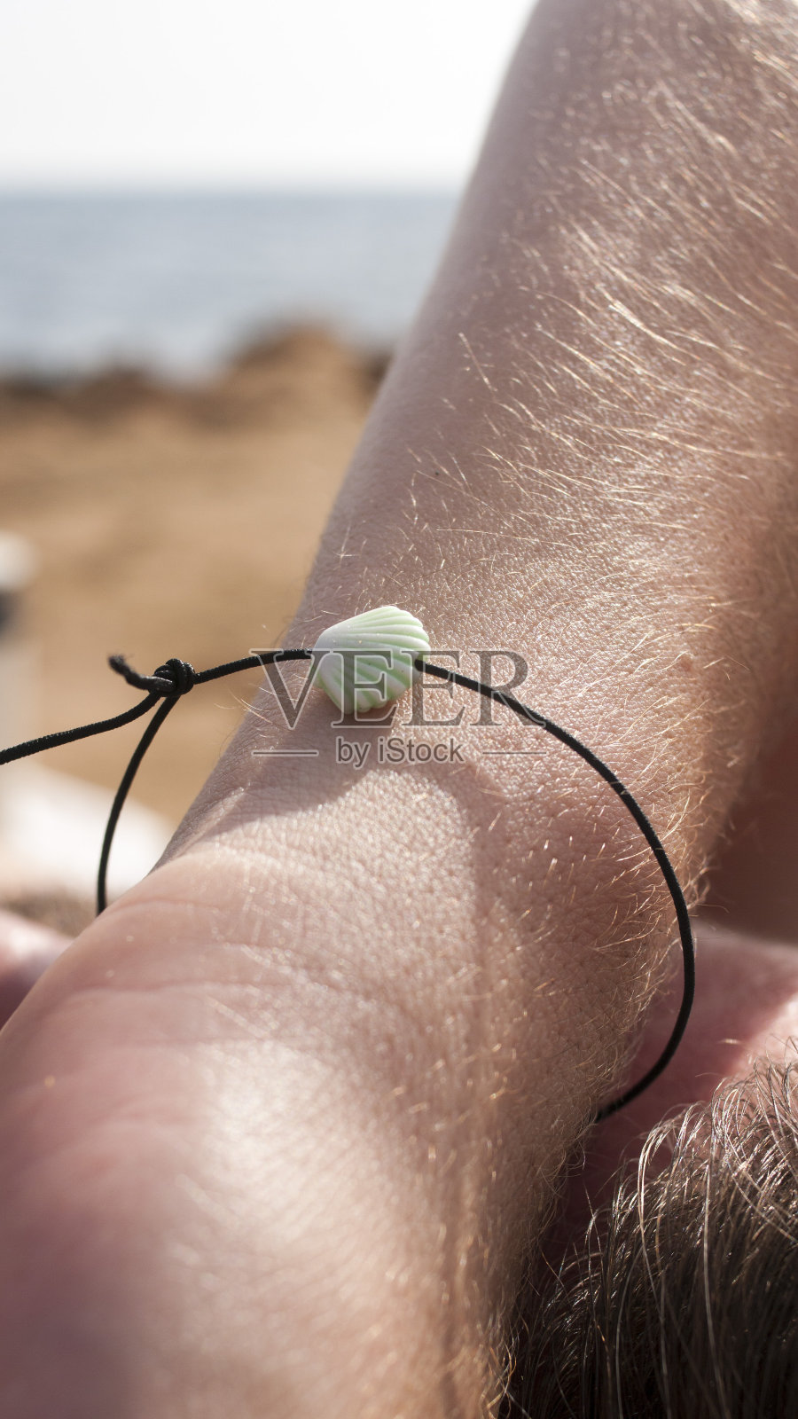 海边一个男人手臂上的小贝壳手腕照片摄影图片