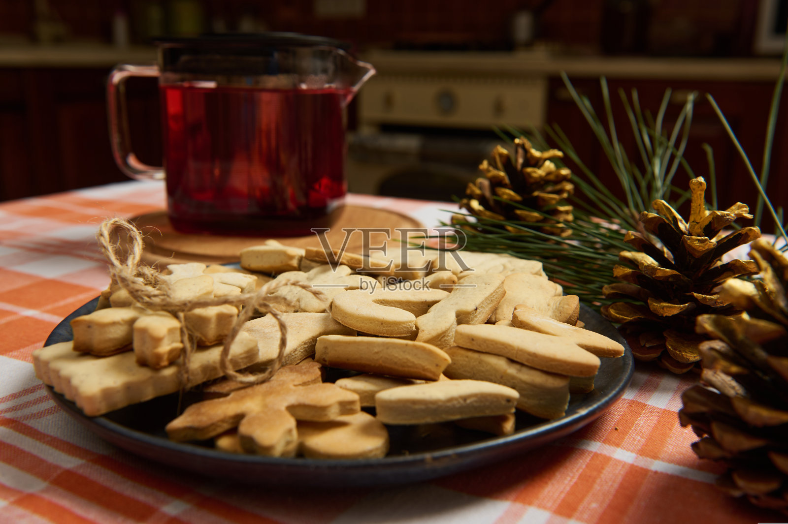 桌上摆着一盘姜饼饼干和木槿茶茶壶，金色的松果是圣诞节的装饰品照片摄影图片