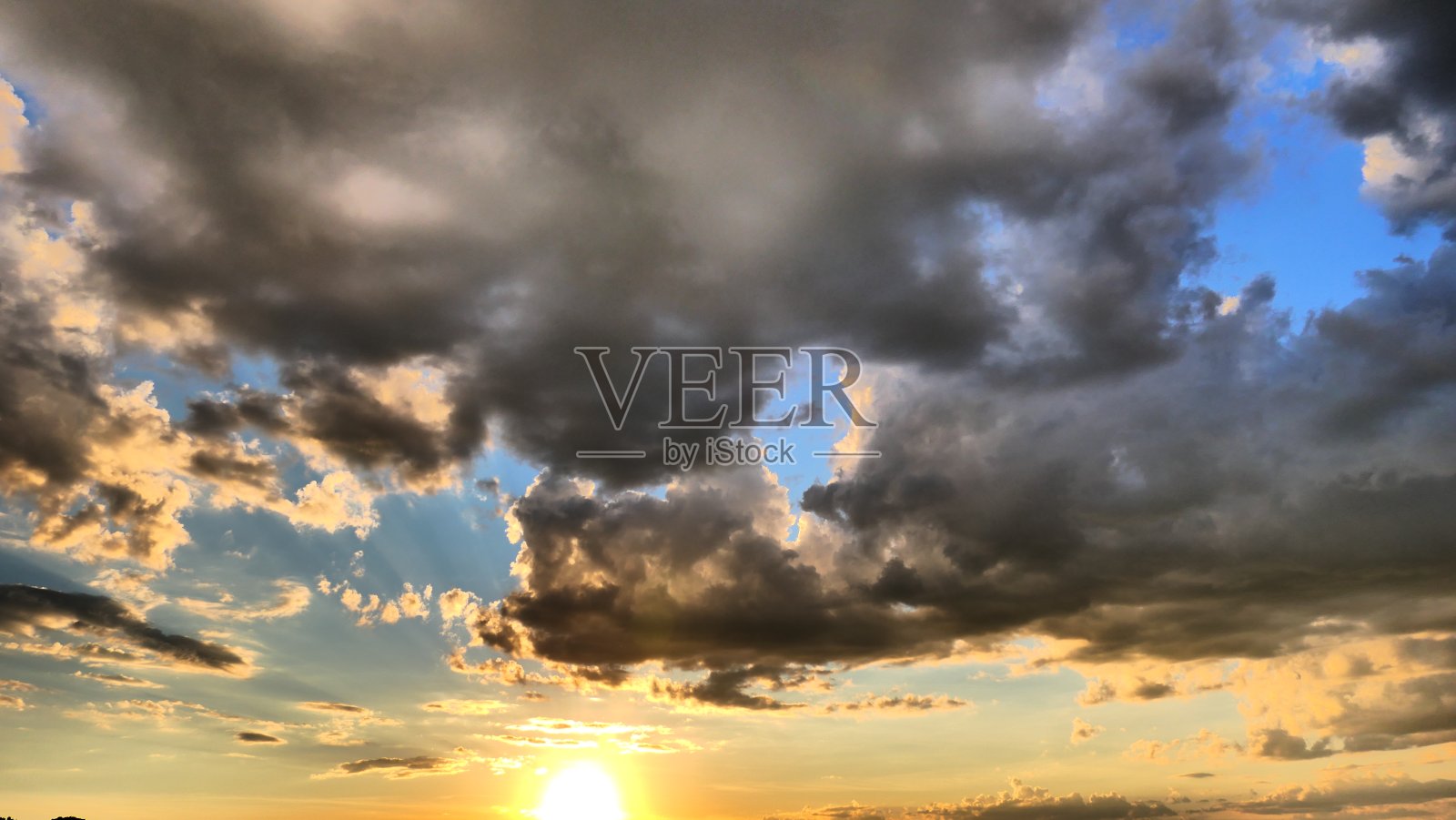 蓝色的天空穿过灰色的云层在太阳之上照片摄影图片