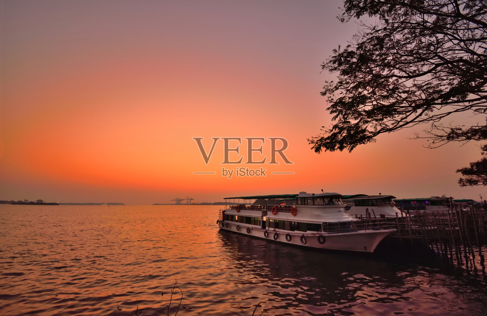 日落时分，停泊在喀拉拉邦滨海大道回水码头上的一艘船。照片摄影图片