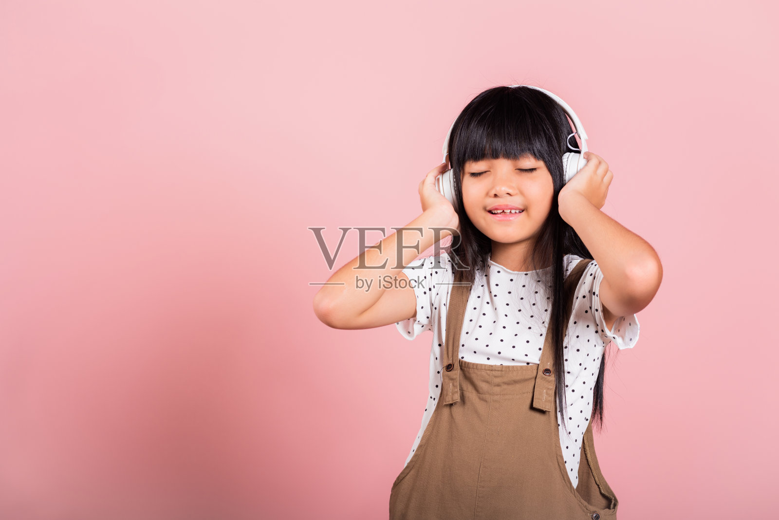 10岁的亚洲小孩，戴着无线耳机，微笑着听音乐照片摄影图片