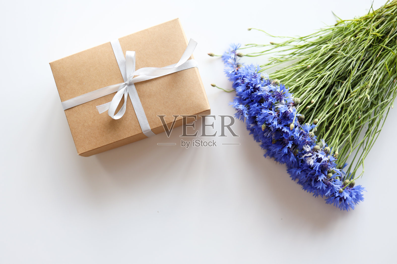 一束美丽的矢车菊花和礼品盒放在轻桌子上，平躺。文本空间照片摄影图片