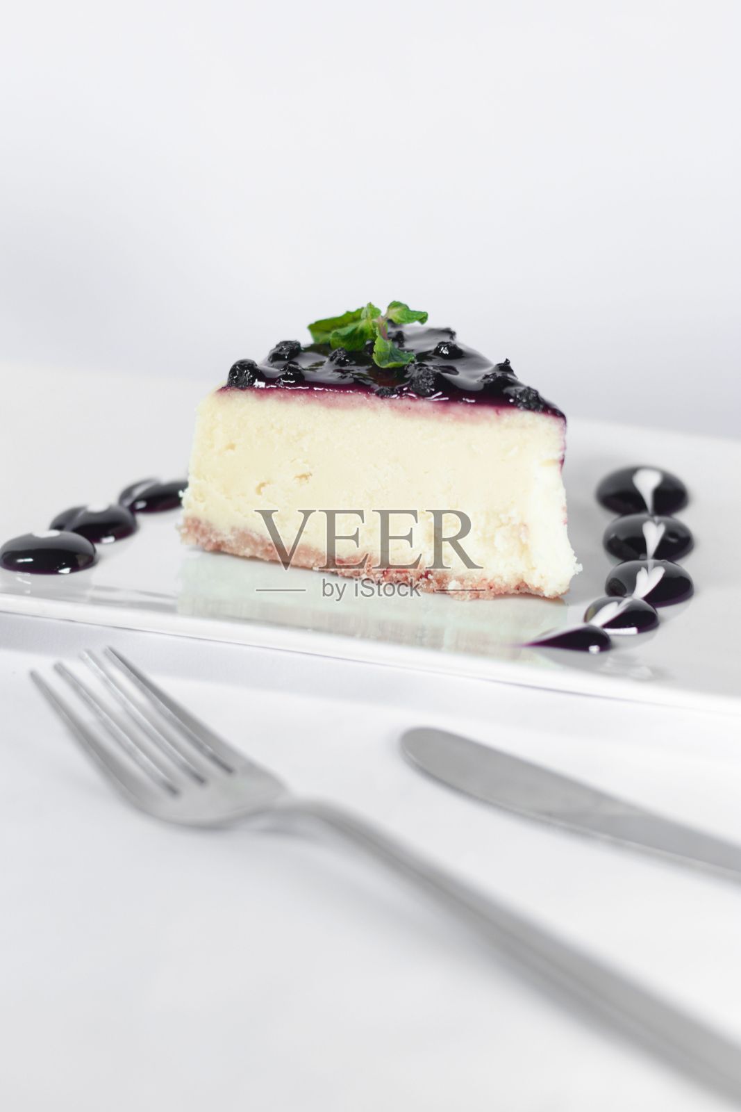 垂直拍摄的樱桃芝士蛋糕在一个白色的盘子，刀和叉在前景照片摄影图片