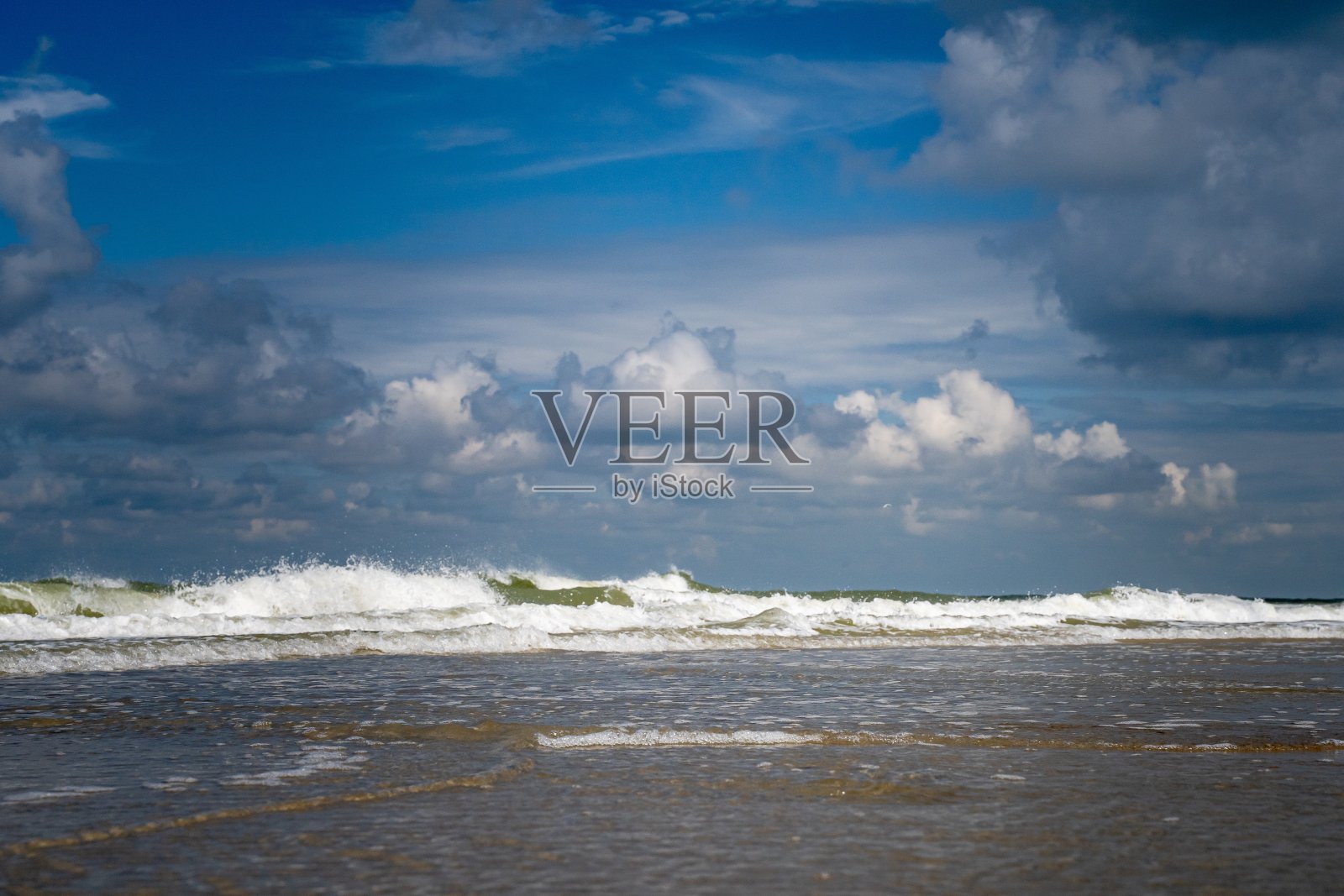 在多云的蓝天下，从海边拍摄的海浪的美丽照片照片摄影图片