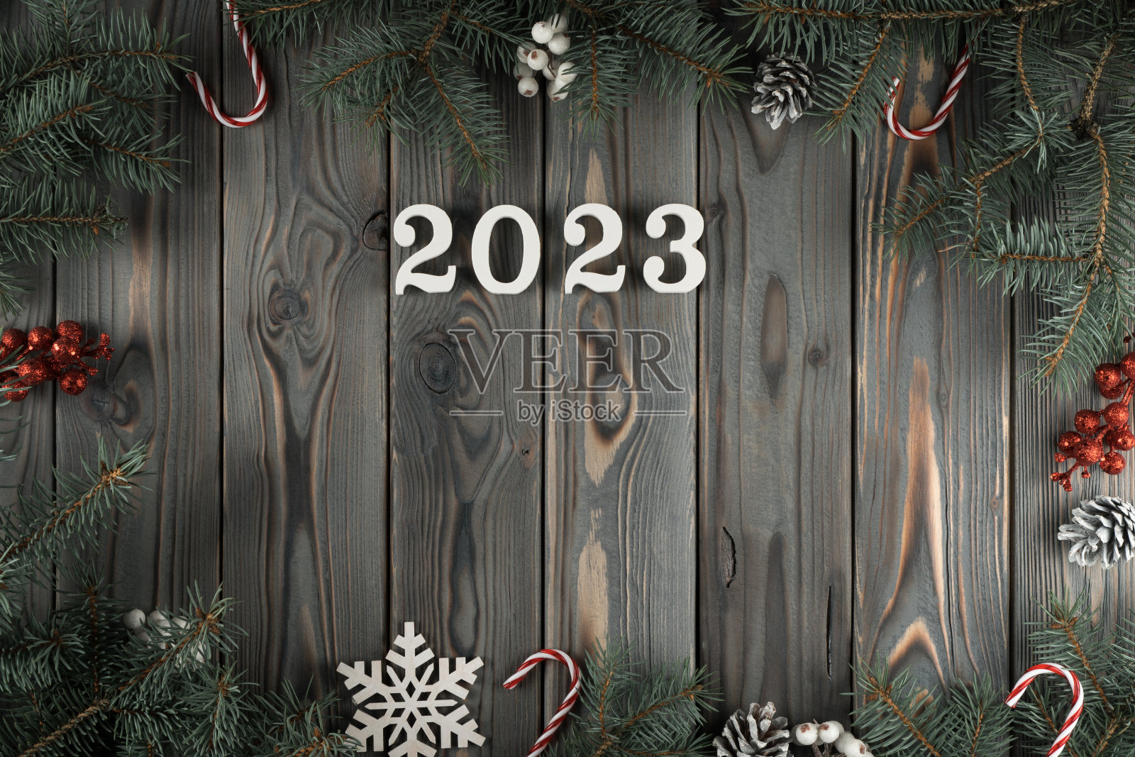 手工装饰框架从云杉树枝灰色木墙，俯瞰。用雪花、球果和棒棒糖装饰的节日。新年佳节概念，庆祝2023年照片摄影图片