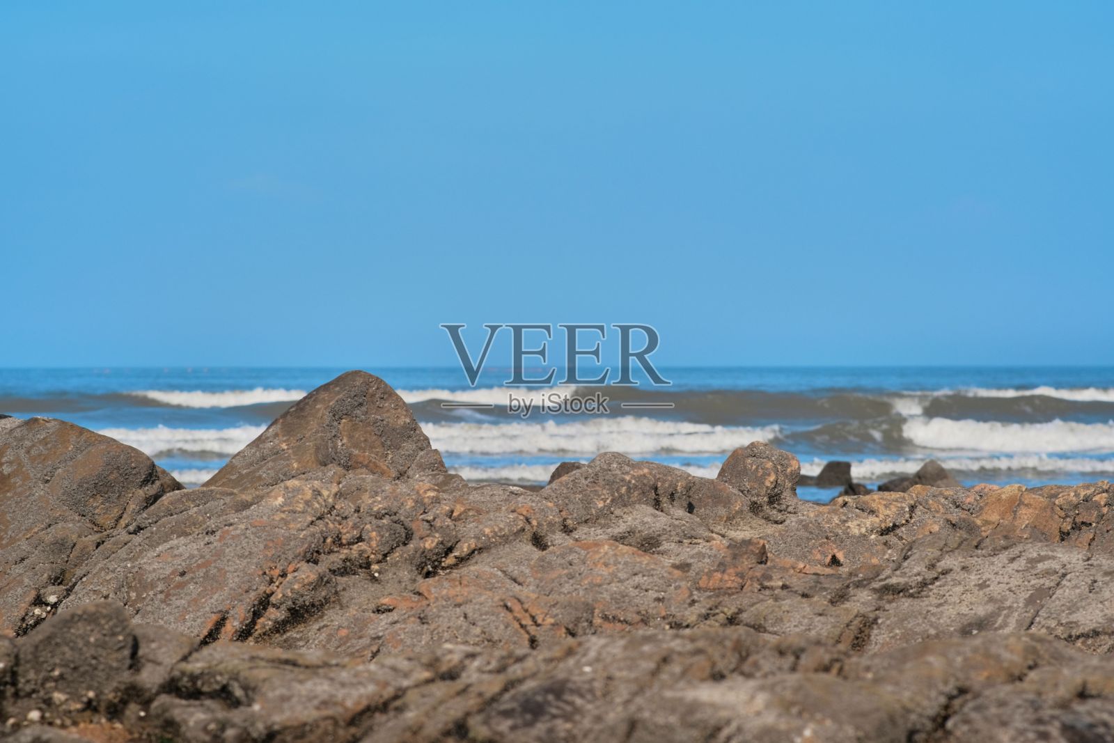 岩石海岸和大海，背景是小波浪照片摄影图片