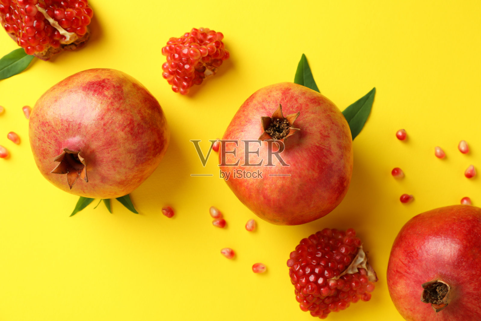 成熟的石榴，叶子和种子在黄色背景照片摄影图片