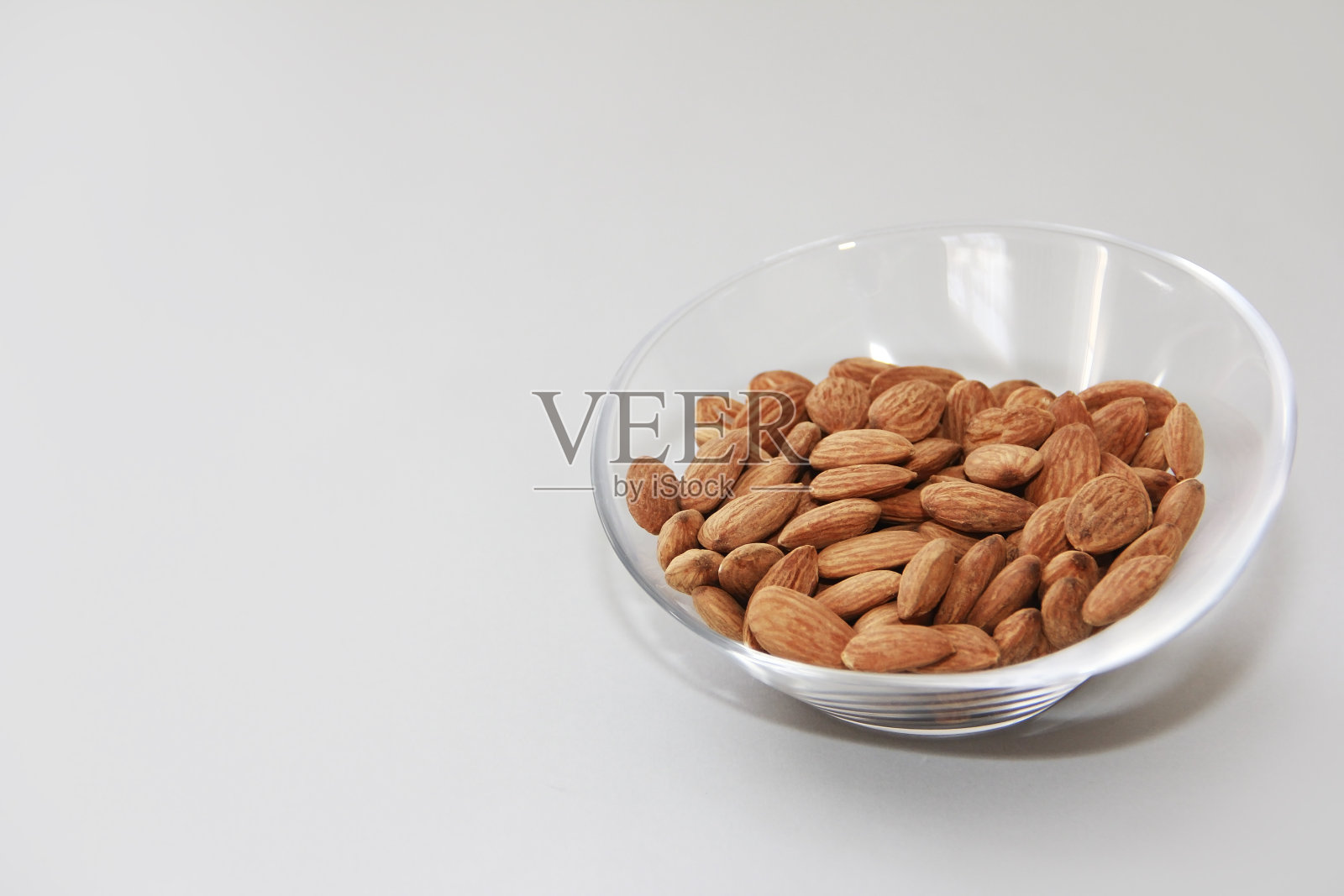 天然棕色杏仁粒装在透明的玻璃盘子里照片摄影图片