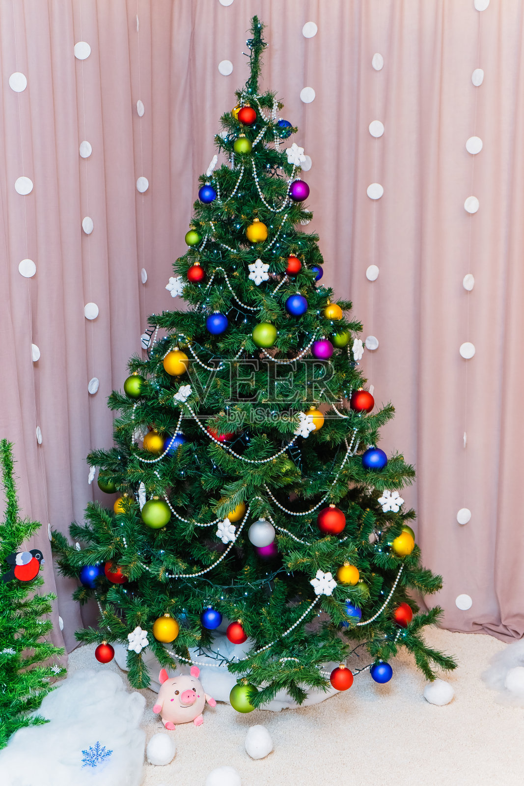 角落里立着一棵圣诞树，上面装饰着彩色气球、白色珠子和发光的电子花环照片摄影图片