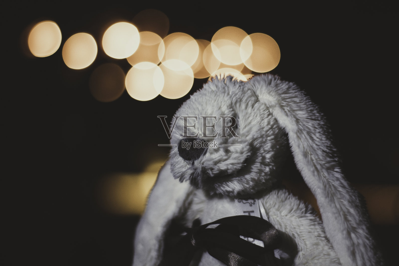 特写一个令人毛骨悚然的白兔娃娃与散景灯在背景-恐怖的概念照片摄影图片