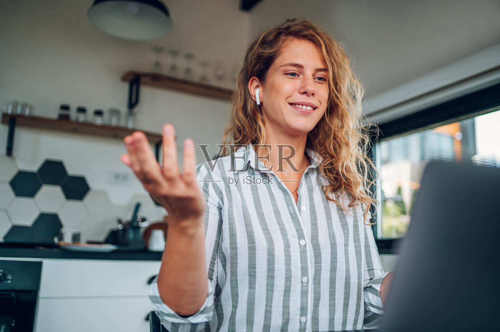 年轻女子在家里用笔记本电脑工作，与同事进行视频通话照片摄影图片