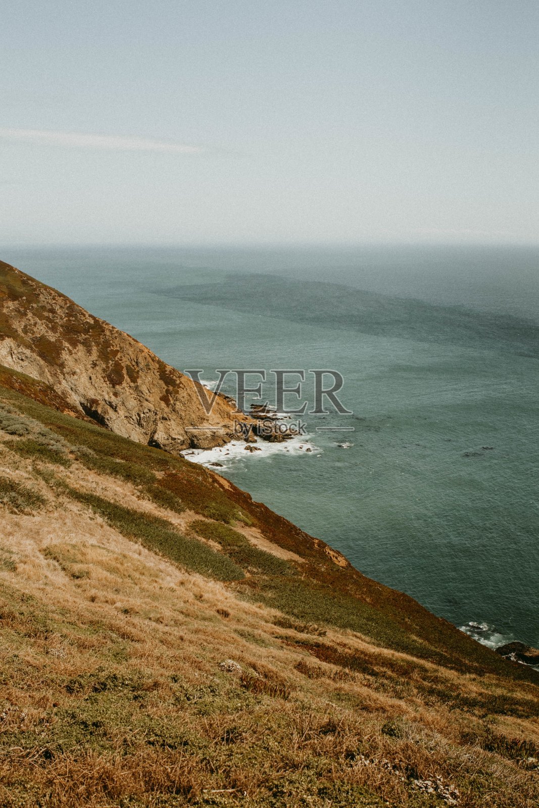 在清澈的天空下，靠水体拍摄的垂直山丘照片摄影图片