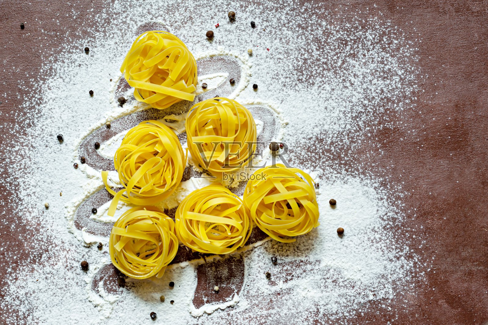 棕色背景下的圣诞树形状的生黄色意大利面(巢)，宽面条，宽面条或意大利宽面条。照片摄影图片