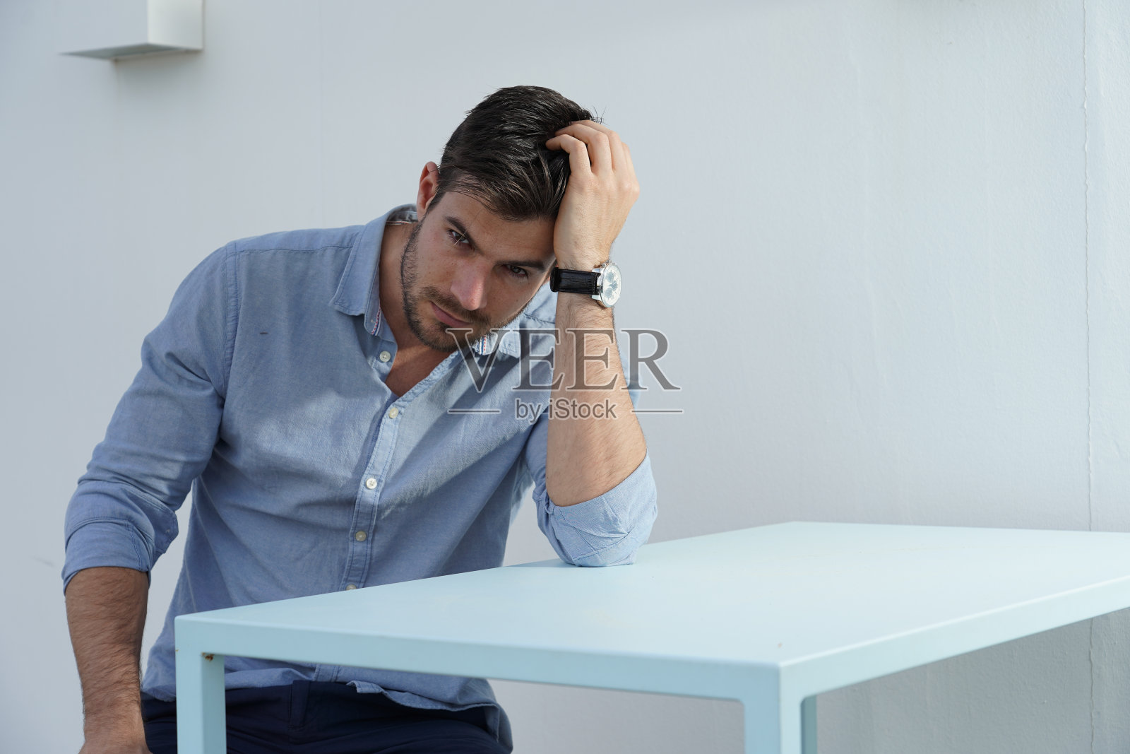 画像一个令人惊叹的男性坐在一个白色家具的房间与淡蓝色的经典衬衫照片摄影图片