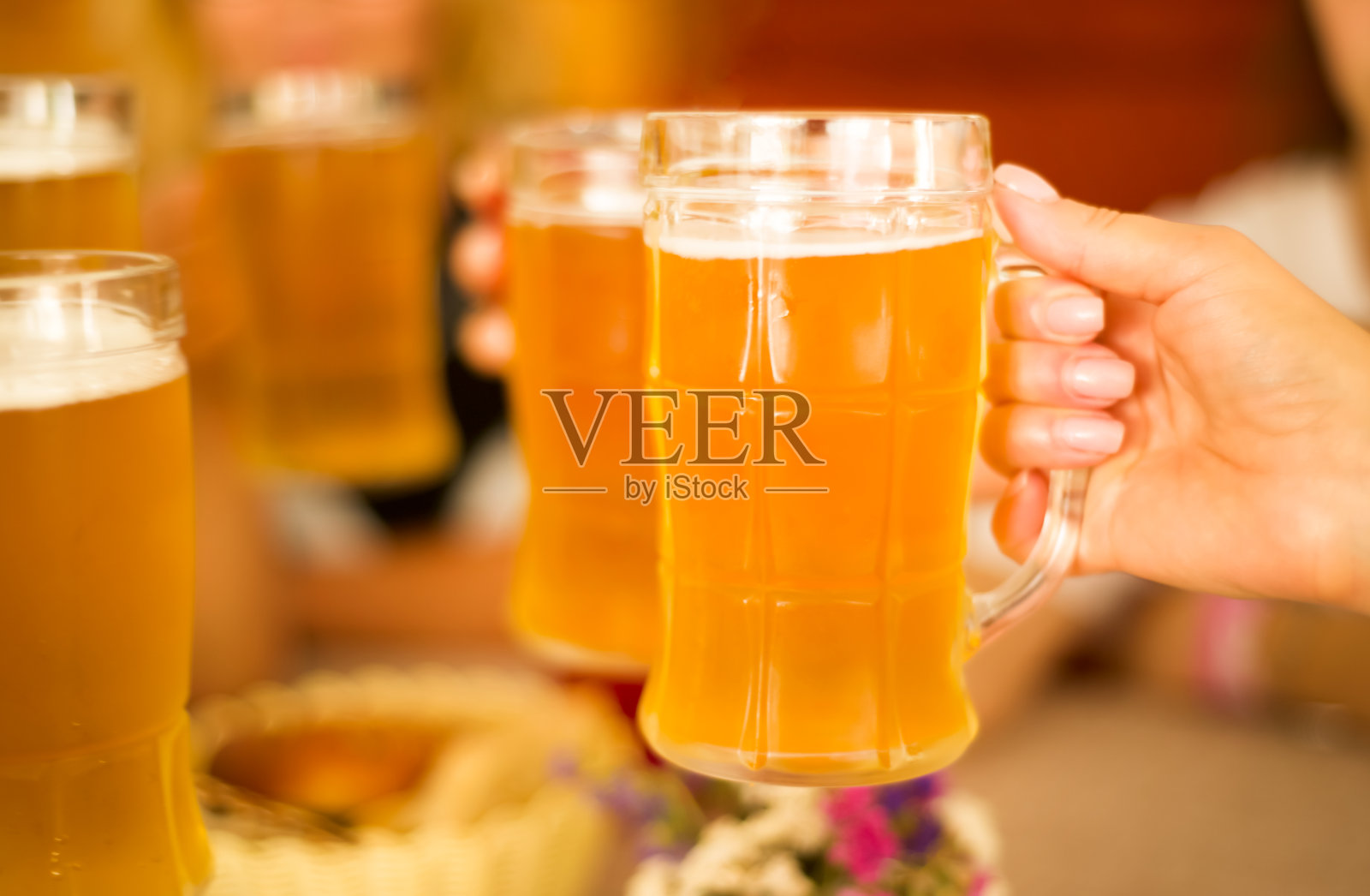 女性朋友在酒吧里喝淡啤酒。美丽的啤酒节背景。女士们拿着啤酒杯的手。照片摄影图片