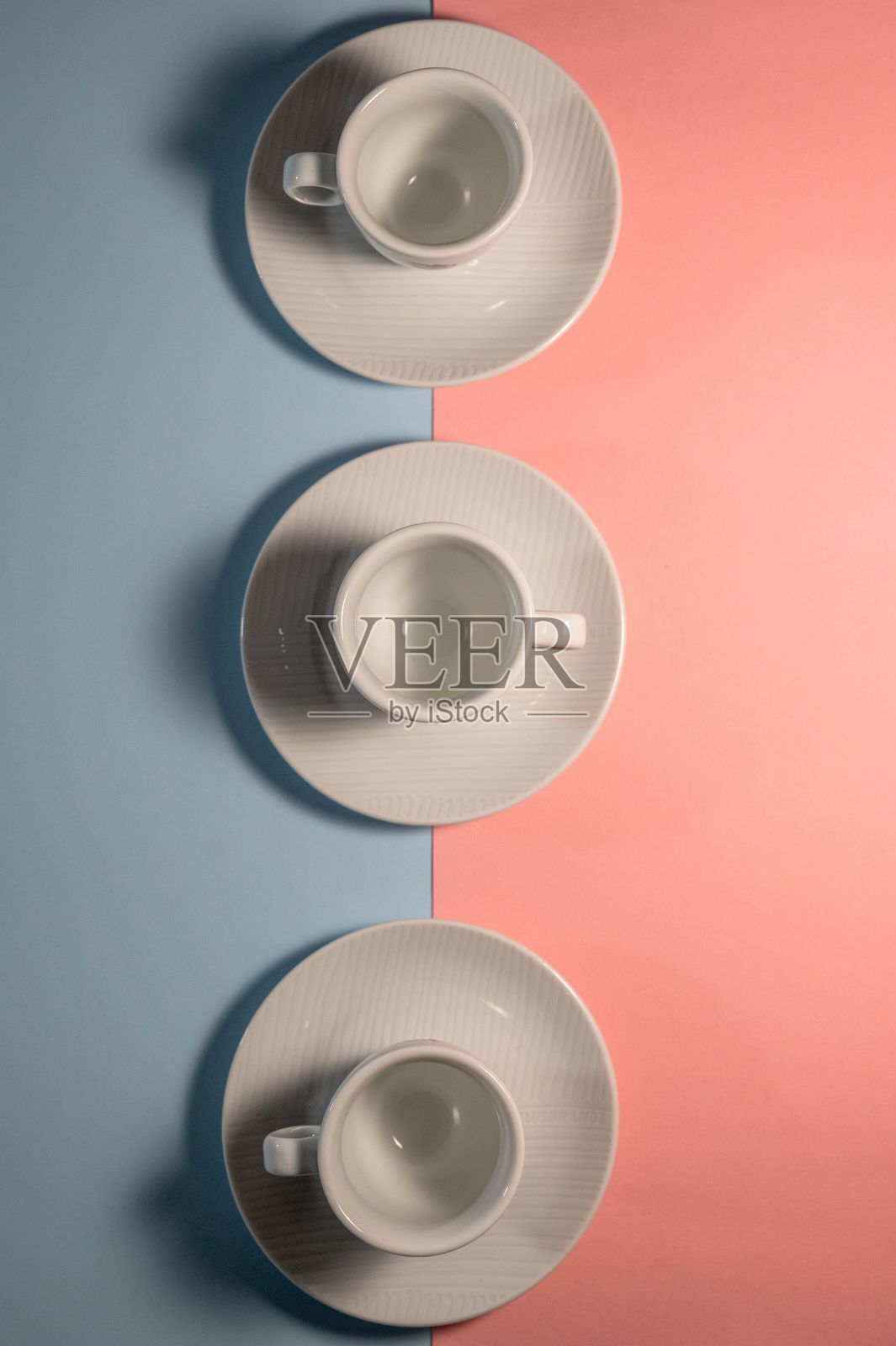 顶视图三个空茶杯的碟子与粉红色和蓝色的背景照片摄影图片