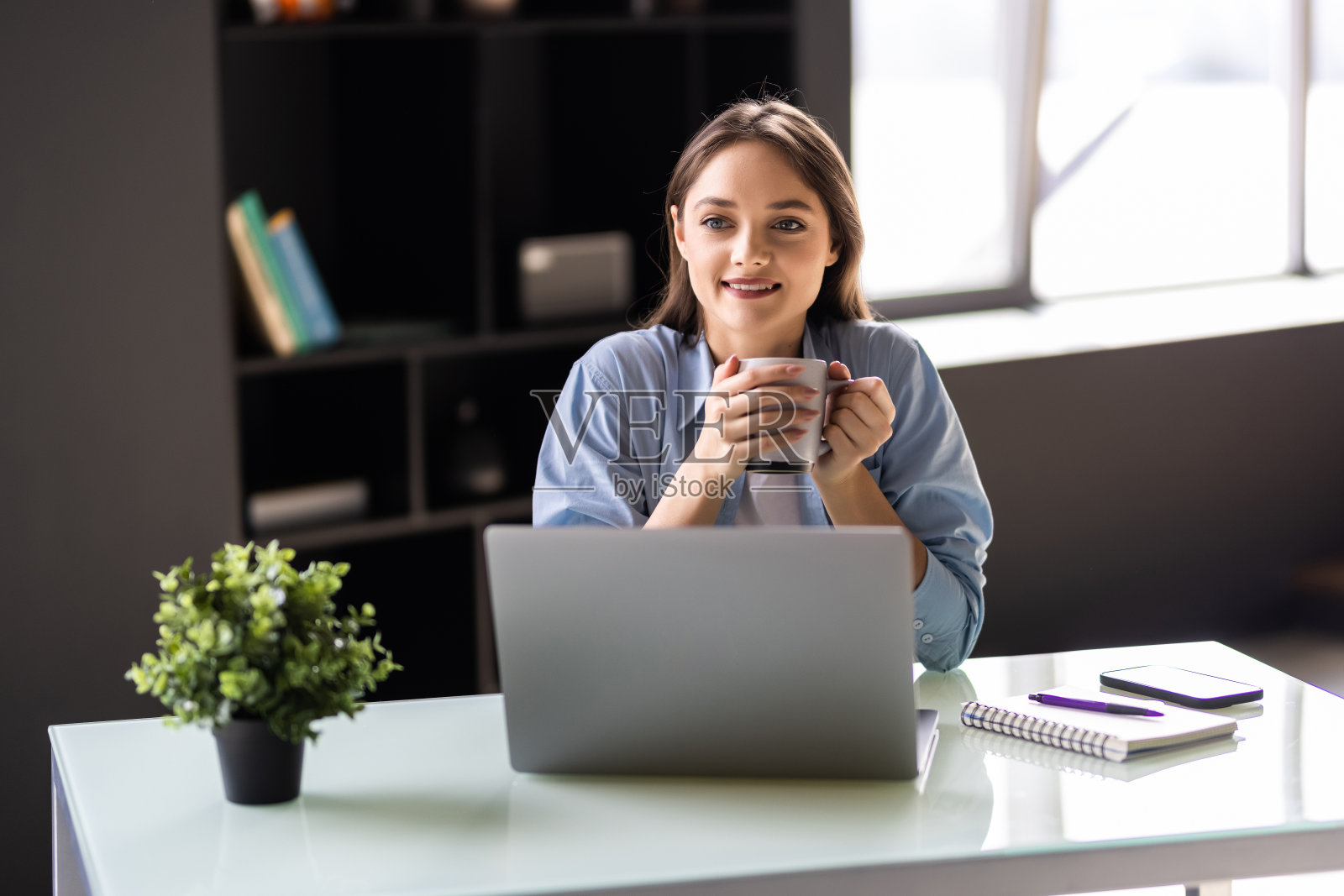 微笑的女人用笔记本电脑工作和喝咖啡照片摄影图片