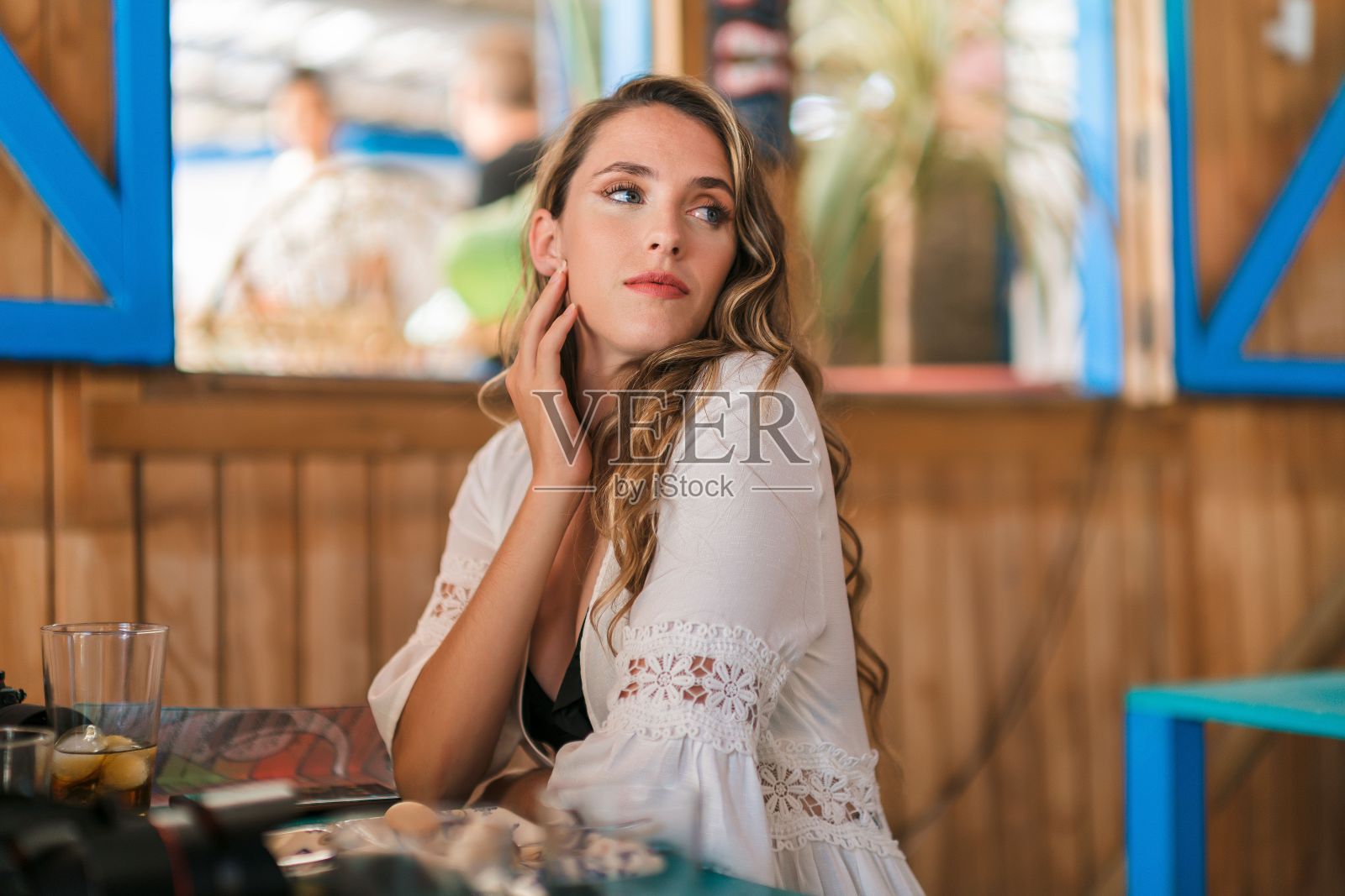 年轻的白人女子坐在海滩附近的咖啡馆里照片摄影图片