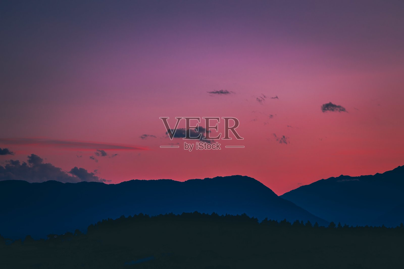 高耸的山脉和森林的剪影，背景是令人窒息的彩色天空照片摄影图片