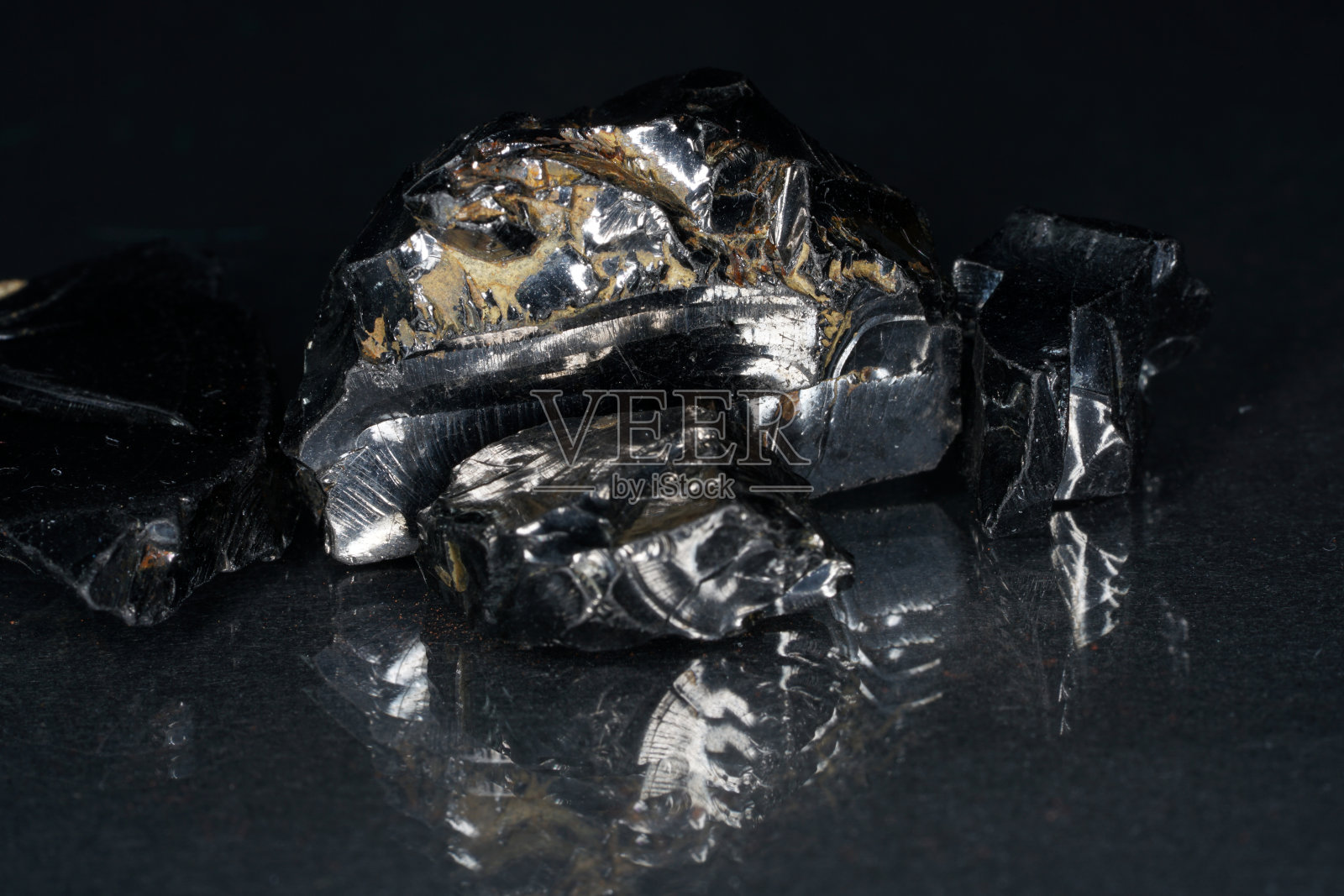 特写镜头的黑色shungite在一个玻璃板在工作室照片摄影图片