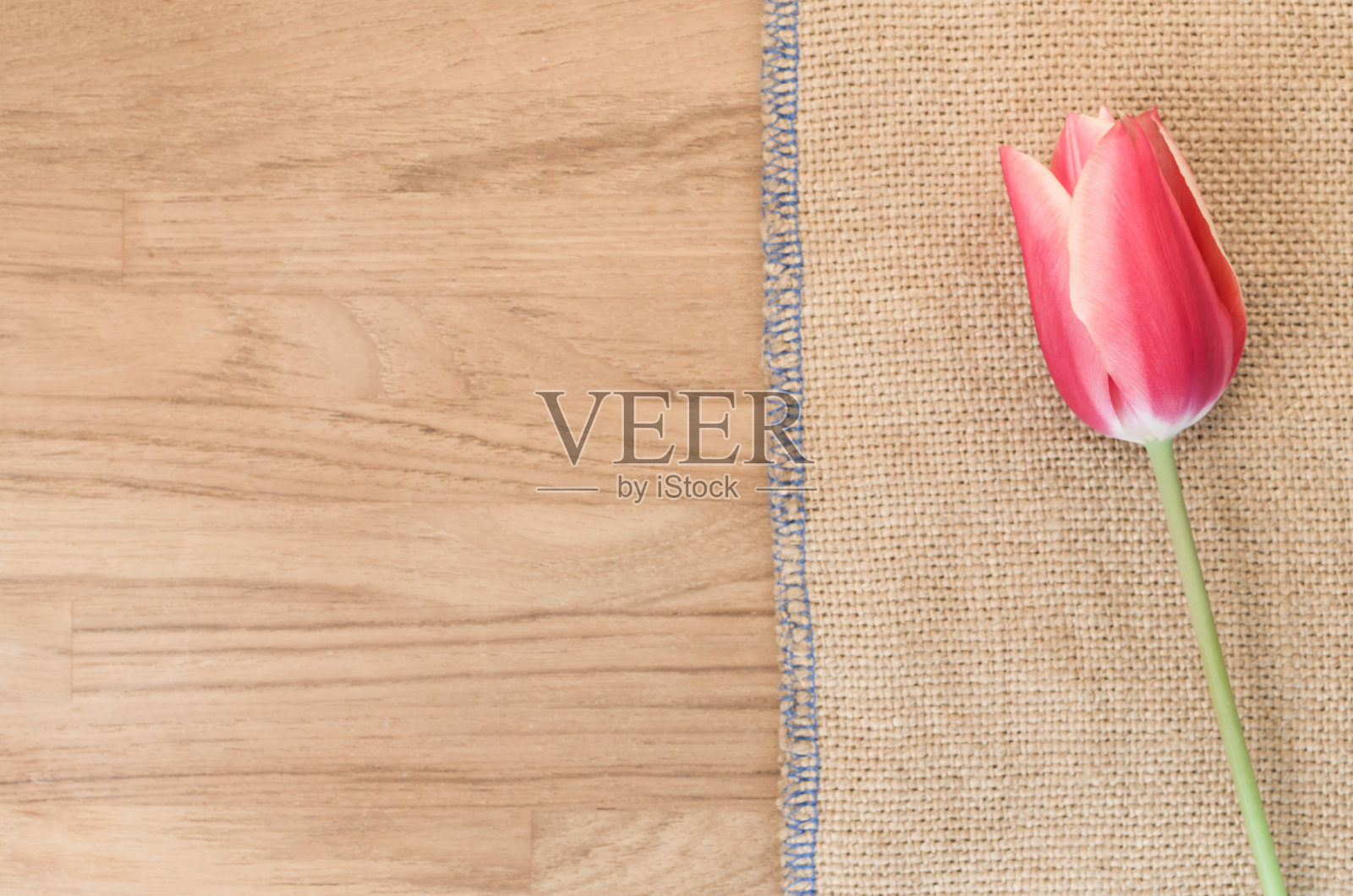 头顶上的一个粉色郁金香花对粗麻布木桌子上的空间为你的文字照片摄影图片