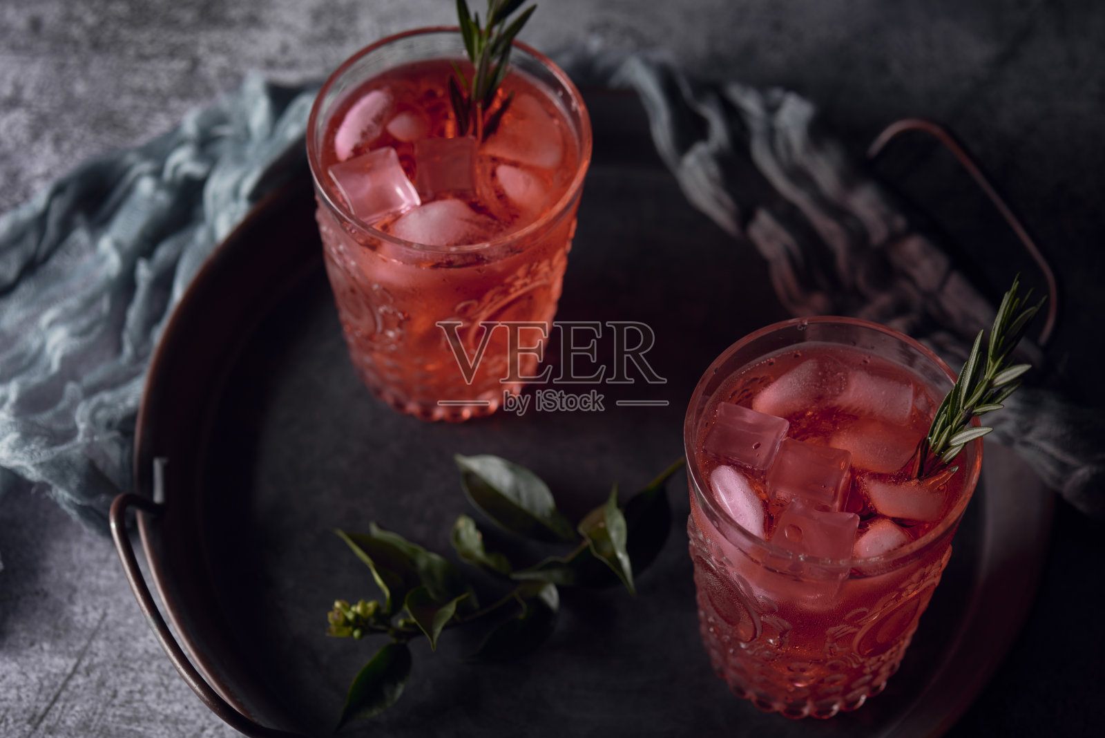 特写镜头红色酒精饮料与迷迭香叶在托盘上照片摄影图片