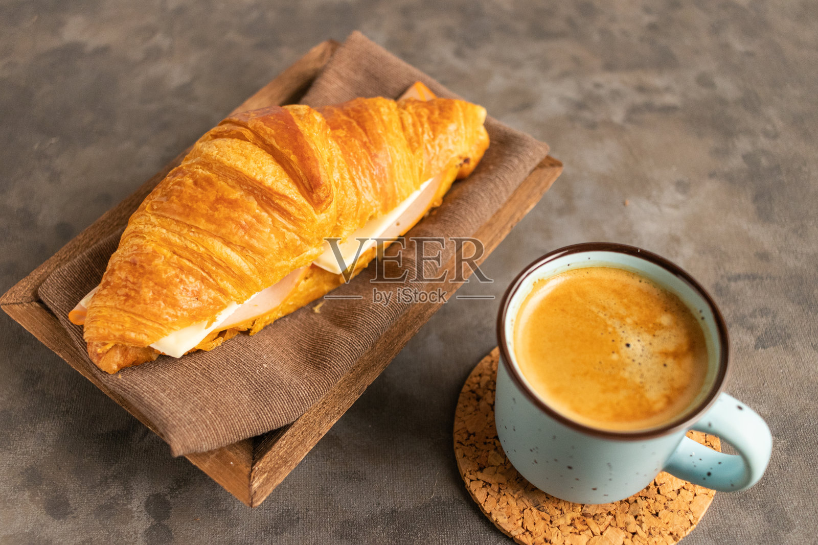 香脆可口的羊角面包配火腿和奶酪馅，桌上还有一杯热咖啡照片摄影图片