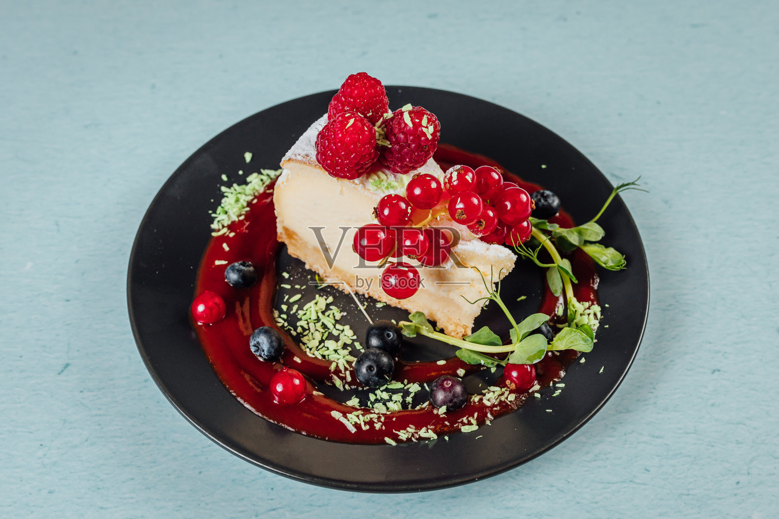 特写的一块美味的奶酪蛋糕与醋栗，覆盆子，蓝莓在盘子上照片摄影图片