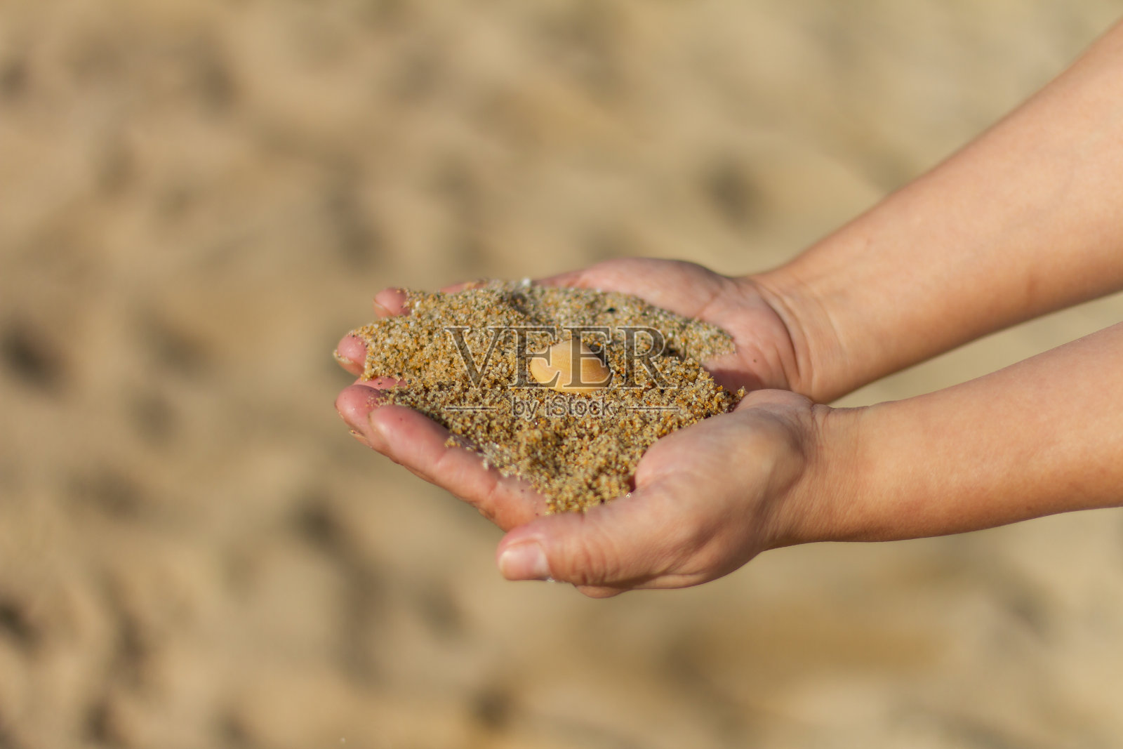 选择性聚焦拍摄手拿沙子，巴塞罗纳塔海滩，巴塞罗那，西班牙照片摄影图片