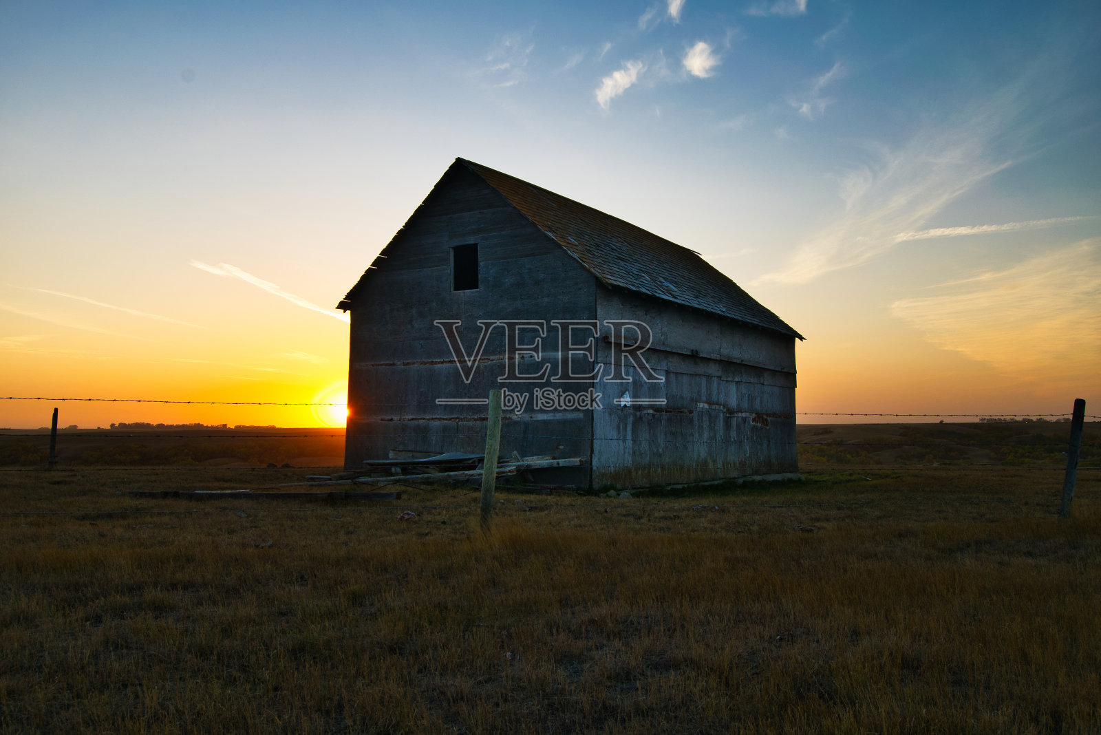 牧场中央的农舍，背景是美丽的日落照片摄影图片