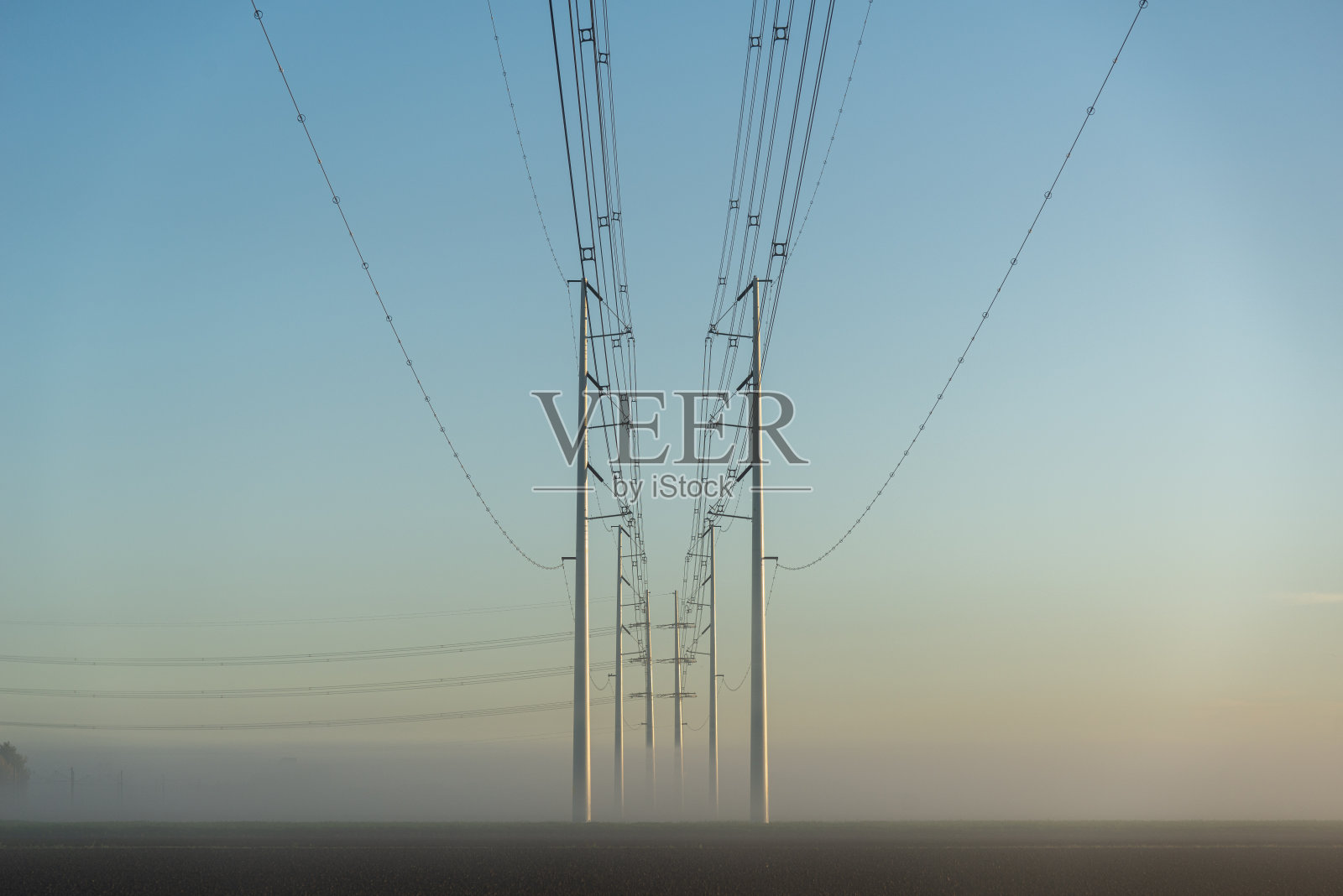 雾蒙蒙日出时的输电塔照片摄影图片