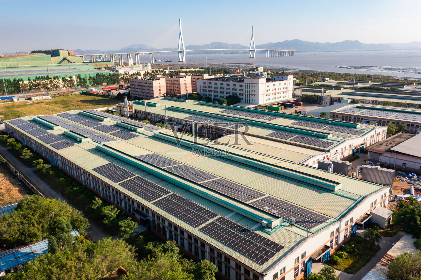 蓝天白云下的工厂屋顶上的太阳能电池板照片摄影图片