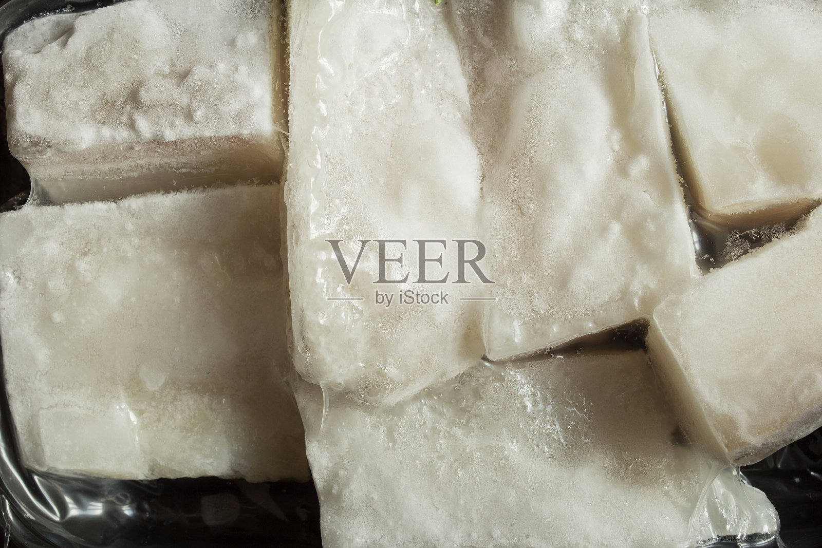 包裹在塑料容器中的冷冻鳕鱼片的特写。照片摄影图片