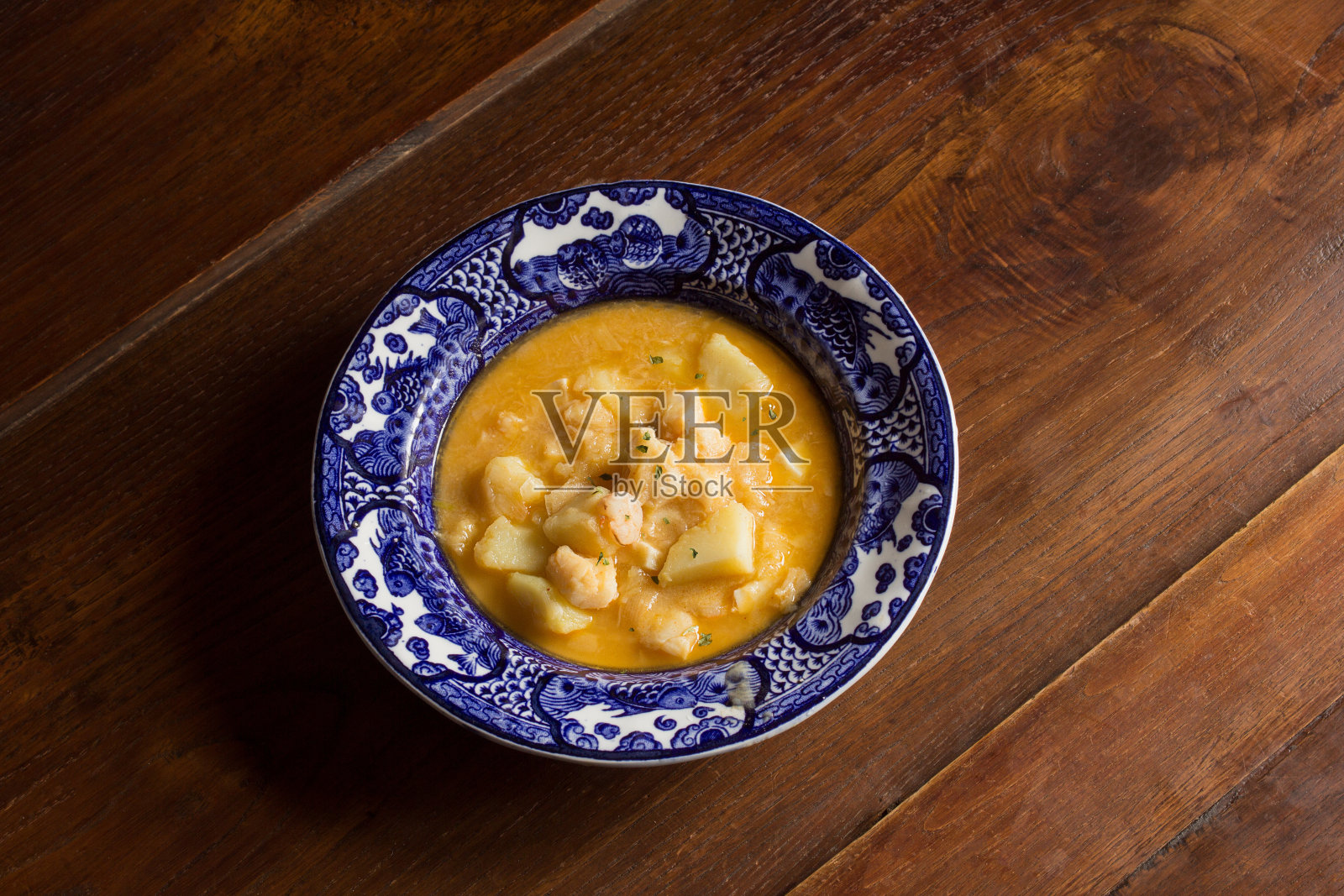 古色古香的盘子装饰着炖鳕鱼和土豆在乡村栗子木背景。照片摄影图片