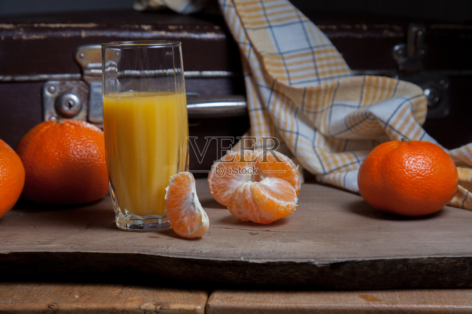 未去皮的圆形成熟橘子或橘子，去皮橘子切片和一杯新鲜果汁放在木板上照片摄影图片