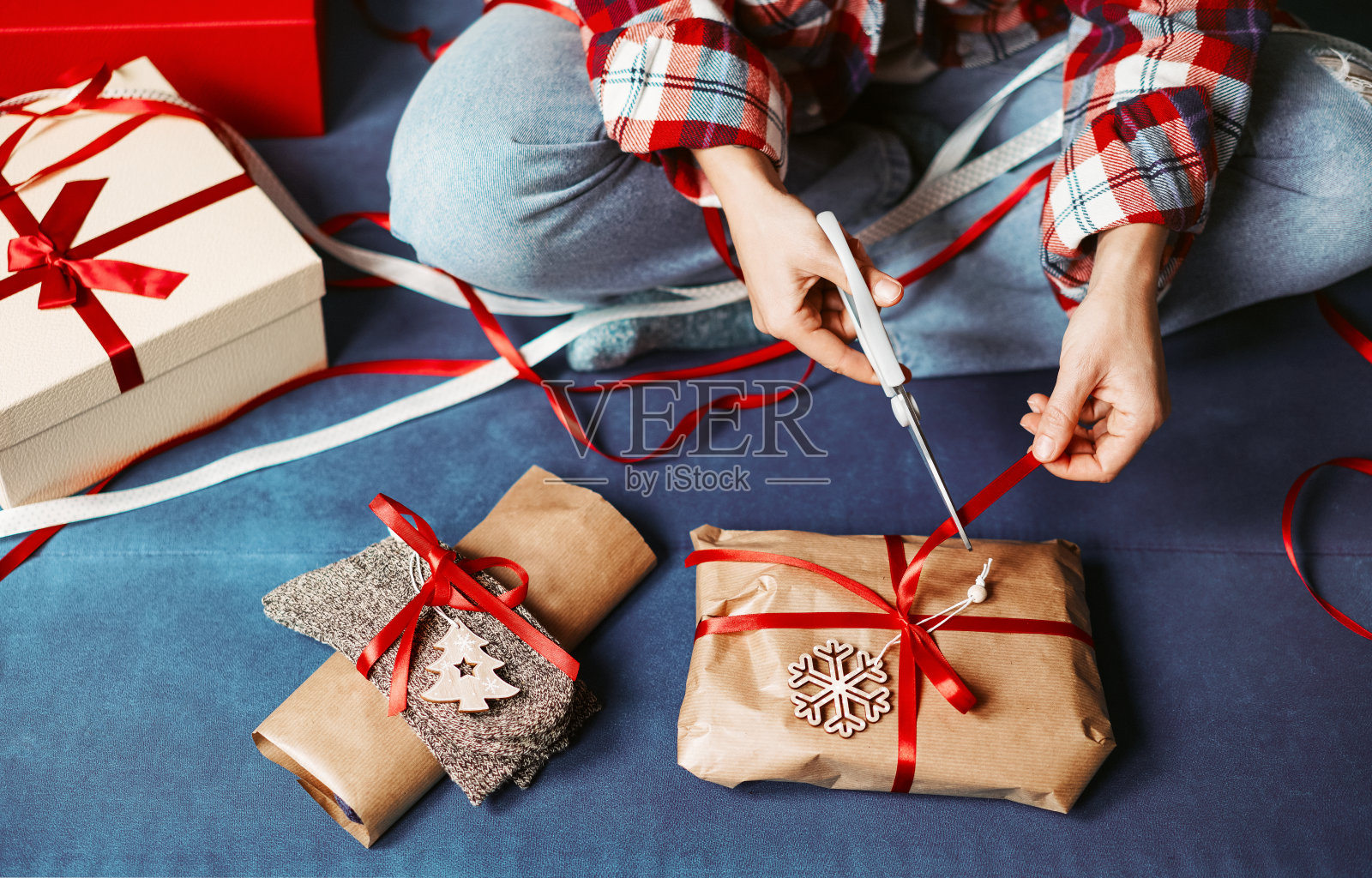 用牛皮纸包装圣诞礼物，剪红丝带。照片摄影图片